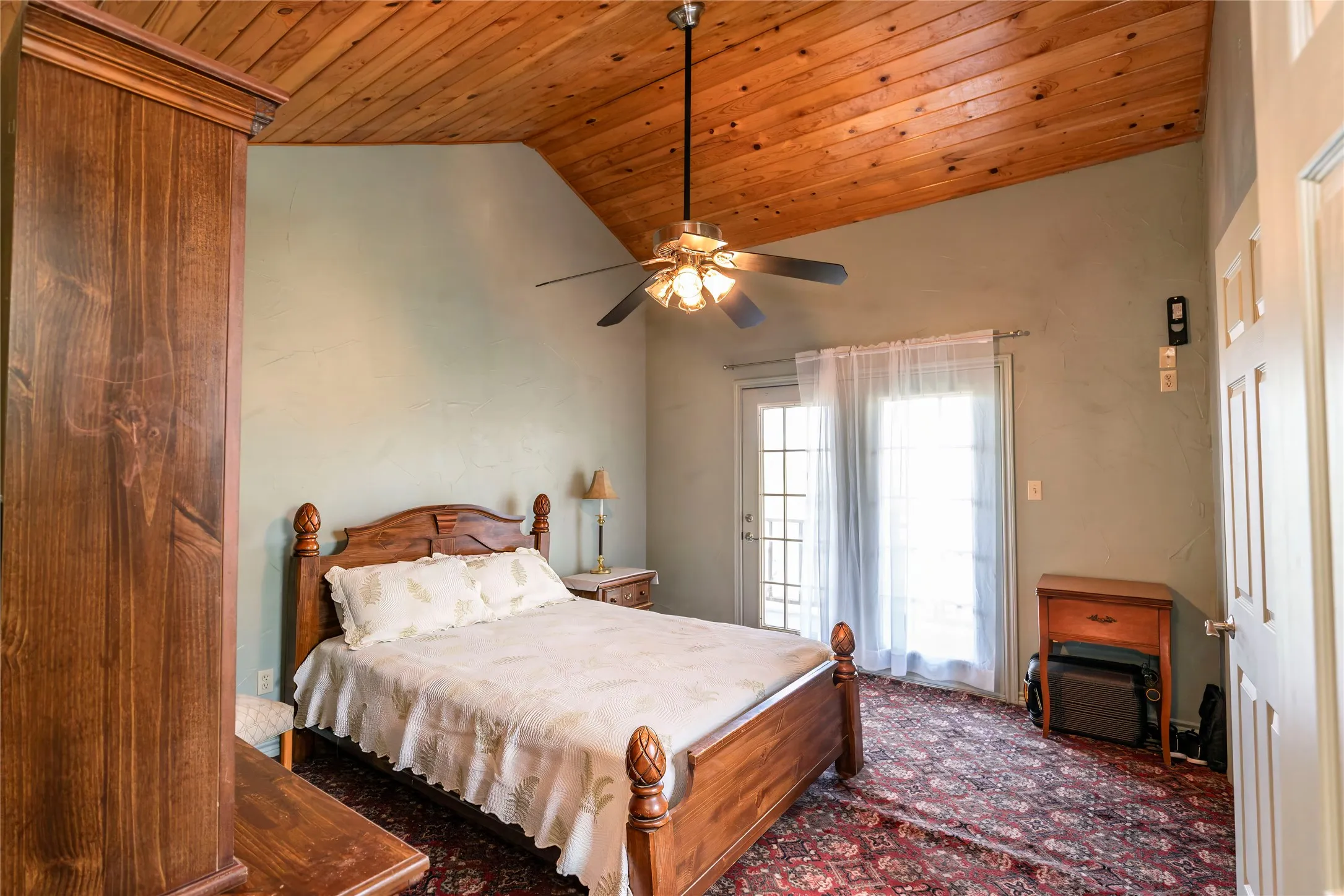 Bedroom featuring wooden ceiling, vaulted ceiling, a ceiling fan, dark colored carpet, and access to exterior