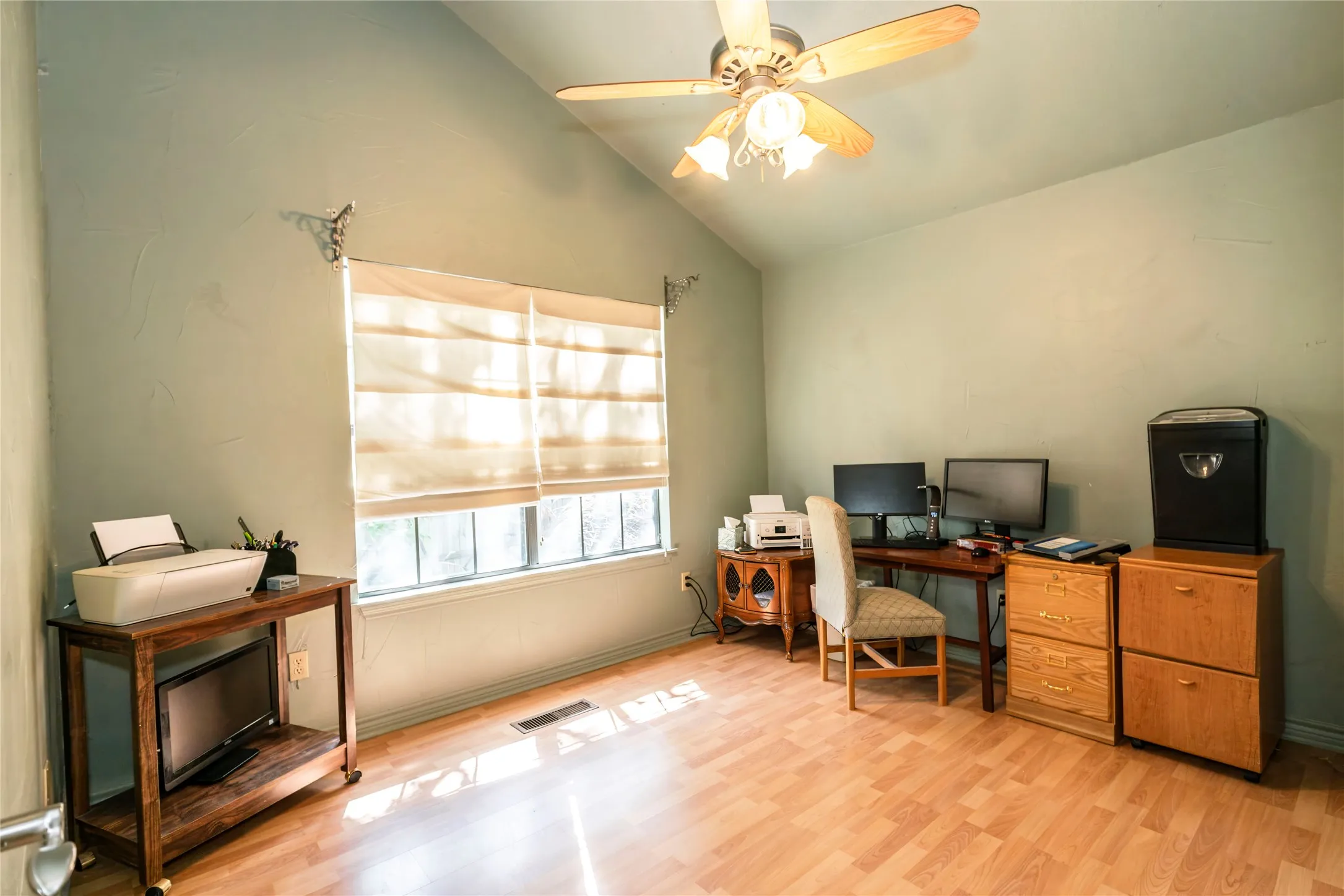 Office space with lofted ceiling, light wood-style floors, and a ceiling fan