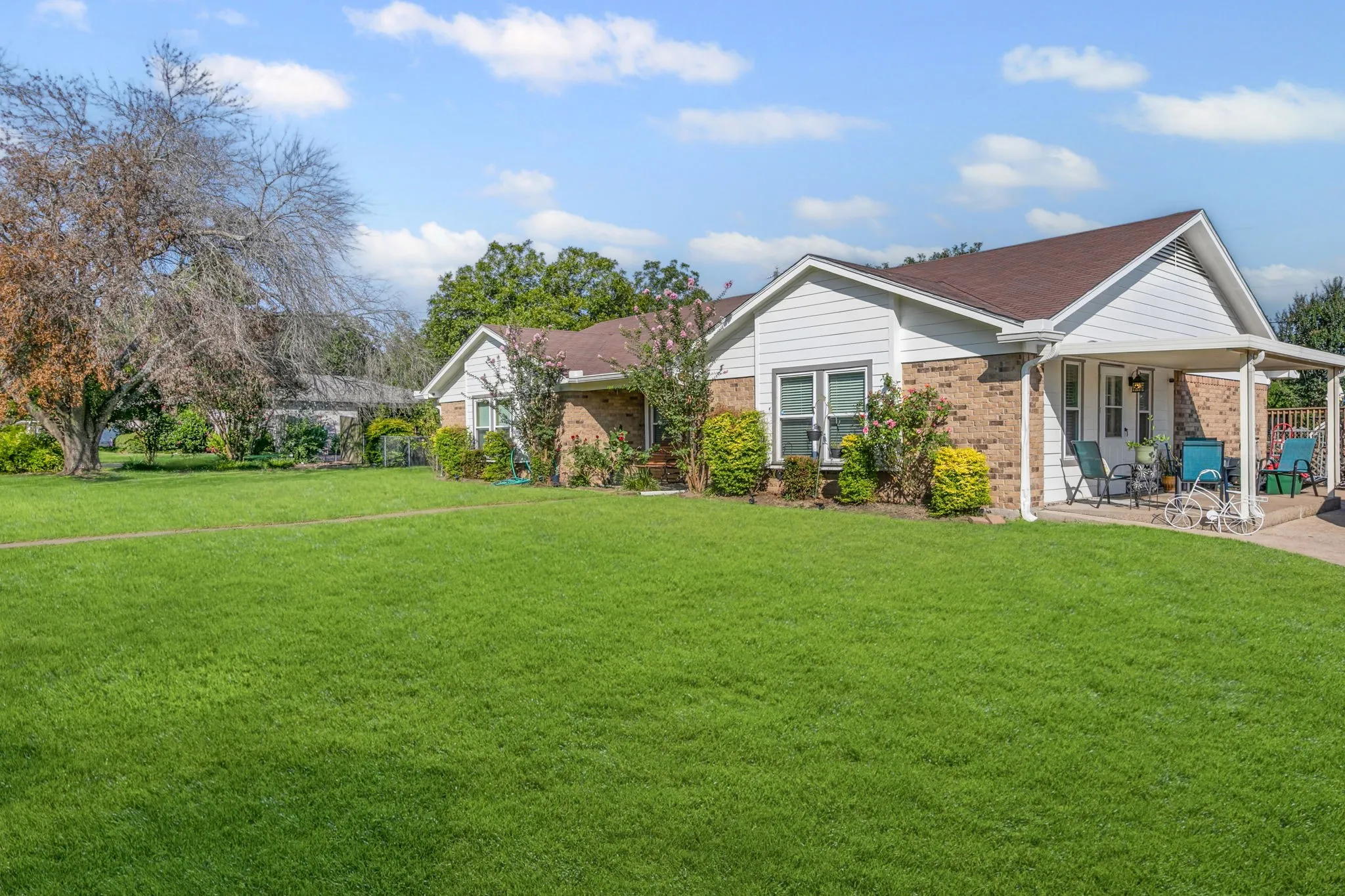 View of front facade featuring brick siding, a front yard, and a patio area