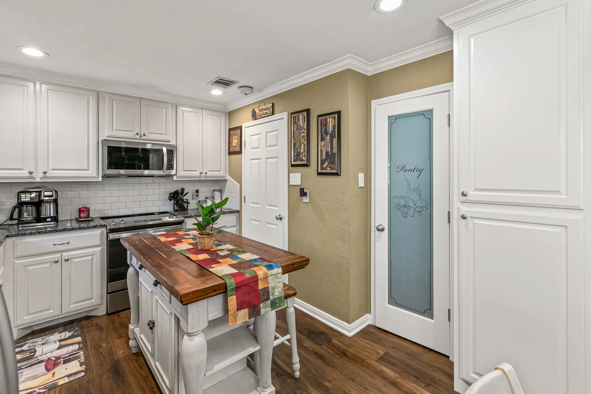 Kitchen featuring stainless steel appliances, dark wood-style flooring, white cabinets, crown molding, and recessed lighting