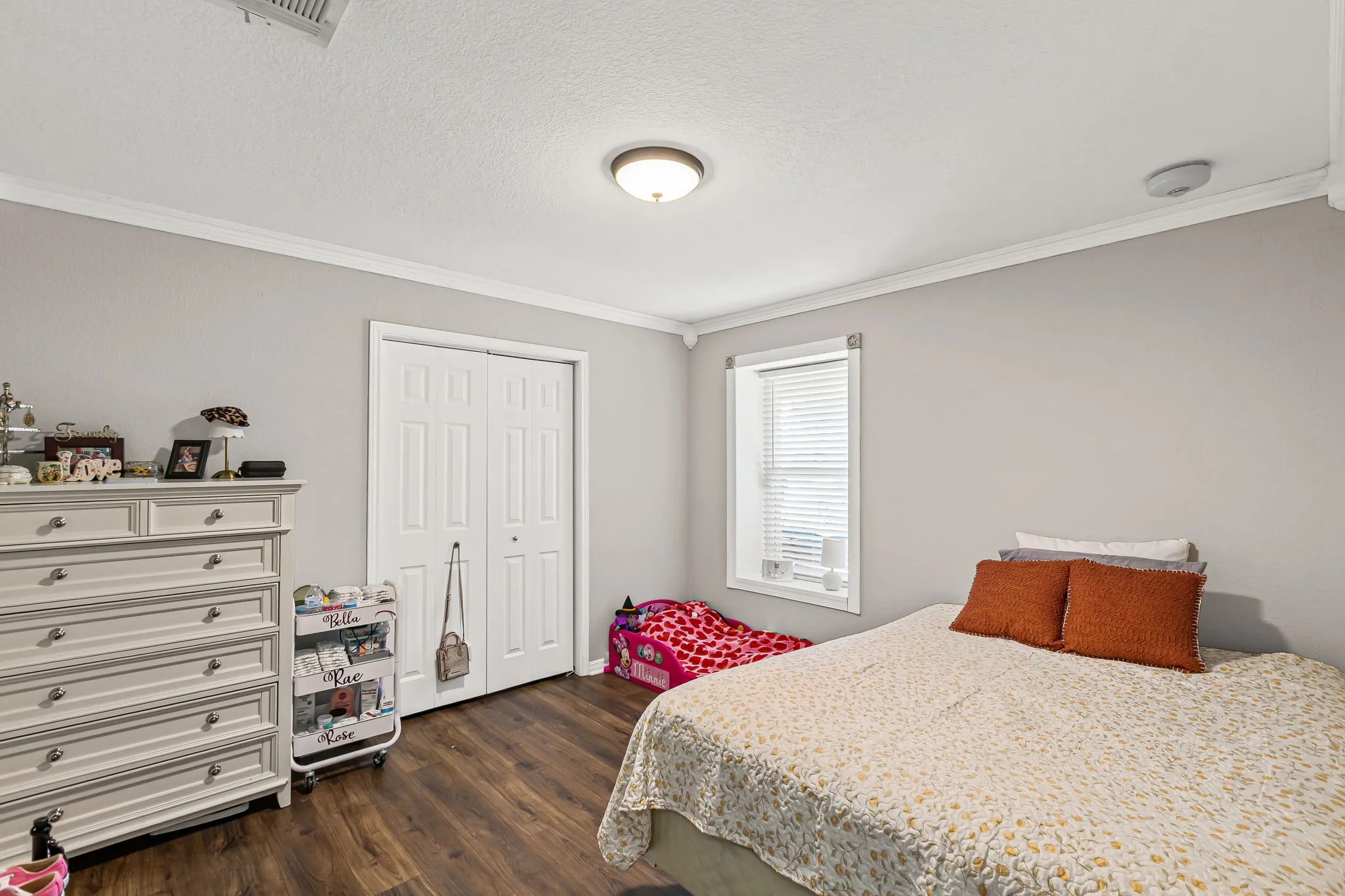 Bedroom with ornamental molding, dark wood-style floors, a closet, and a textured ceiling
