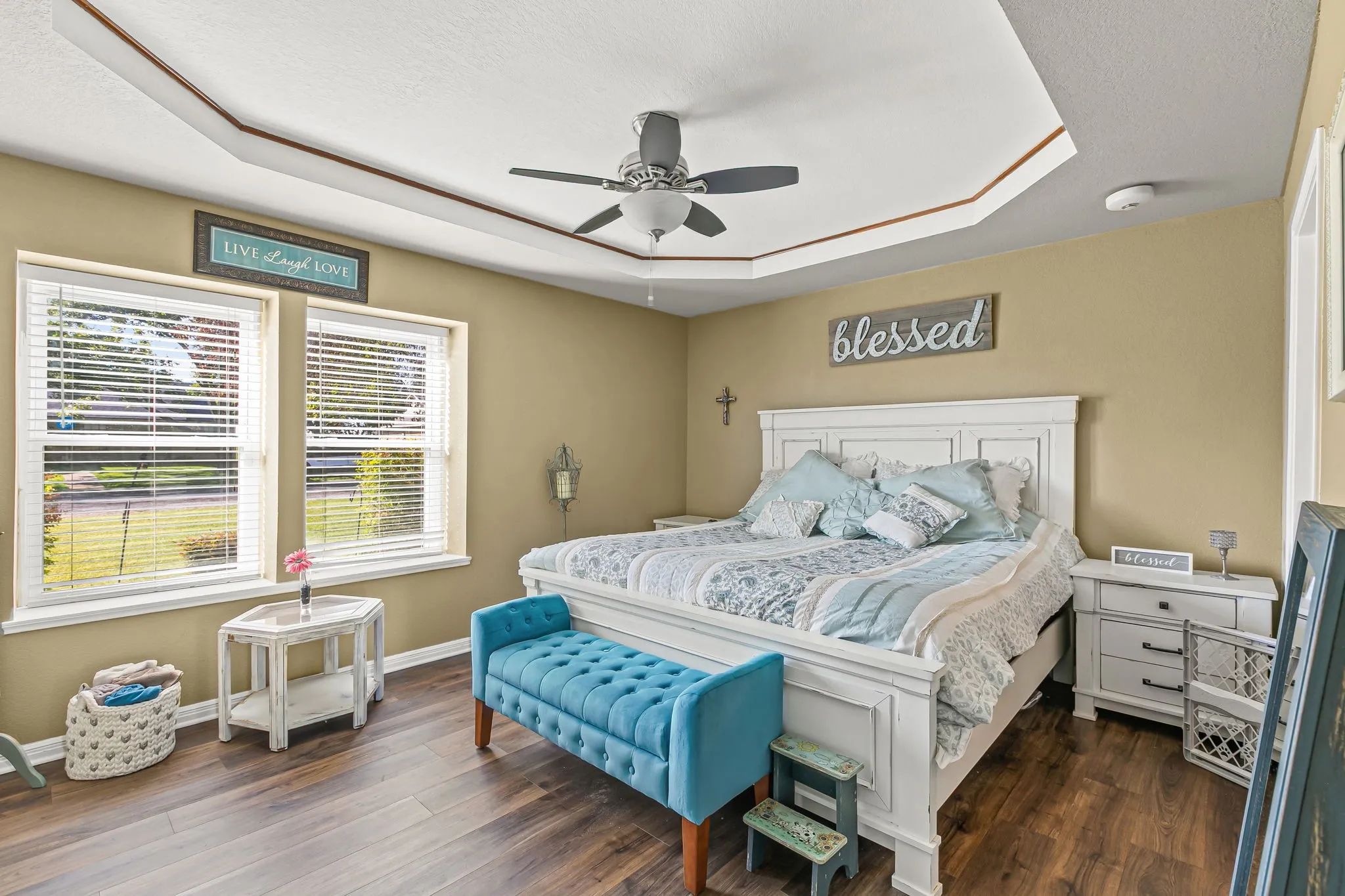 Bedroom with a raised ceiling, dark wood-style flooring, ceiling fan, and a textured ceiling