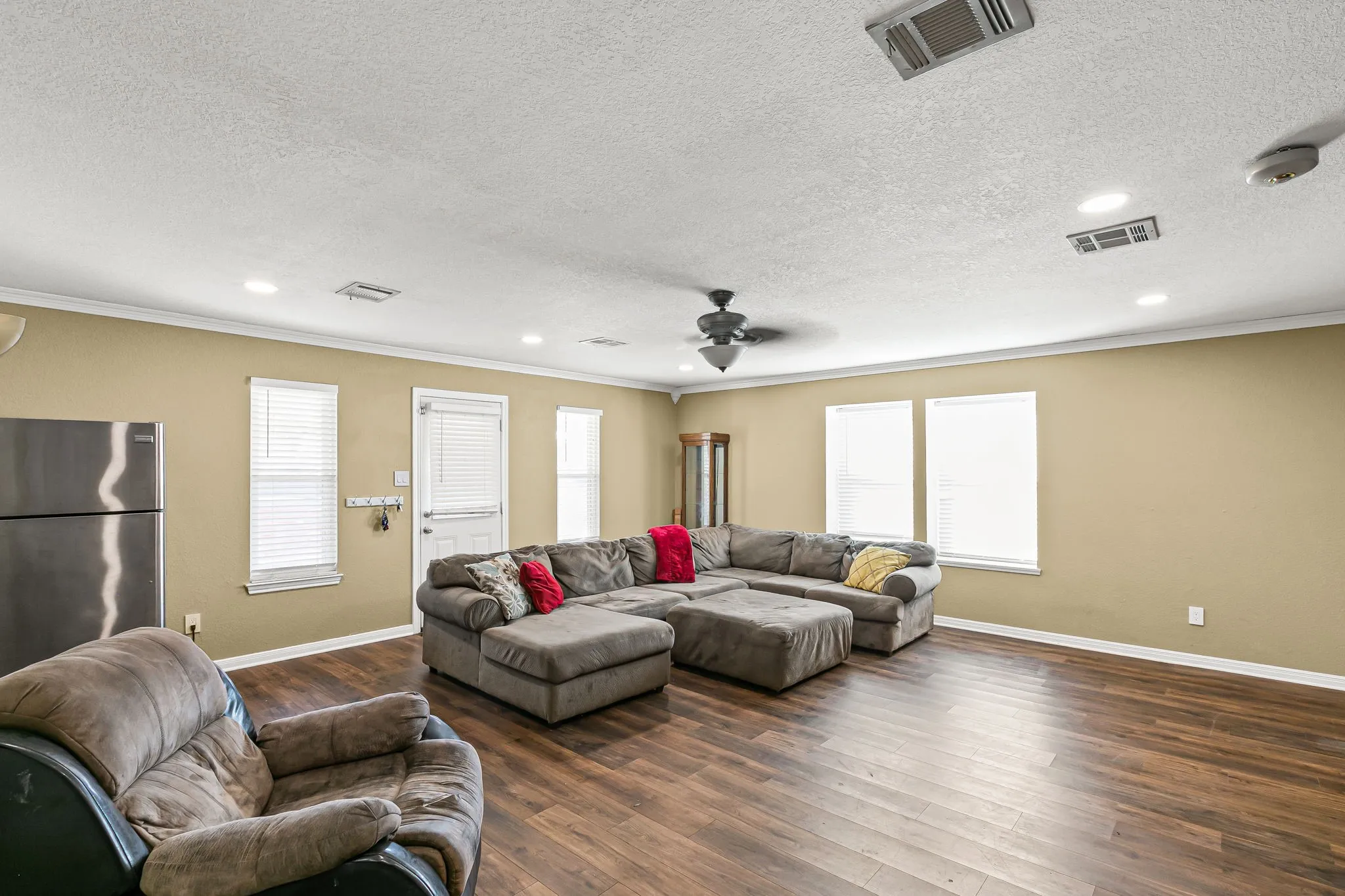 Living area with plenty of natural light, dark wood finished floors, ornamental molding, recessed lighting, and a ceiling fan