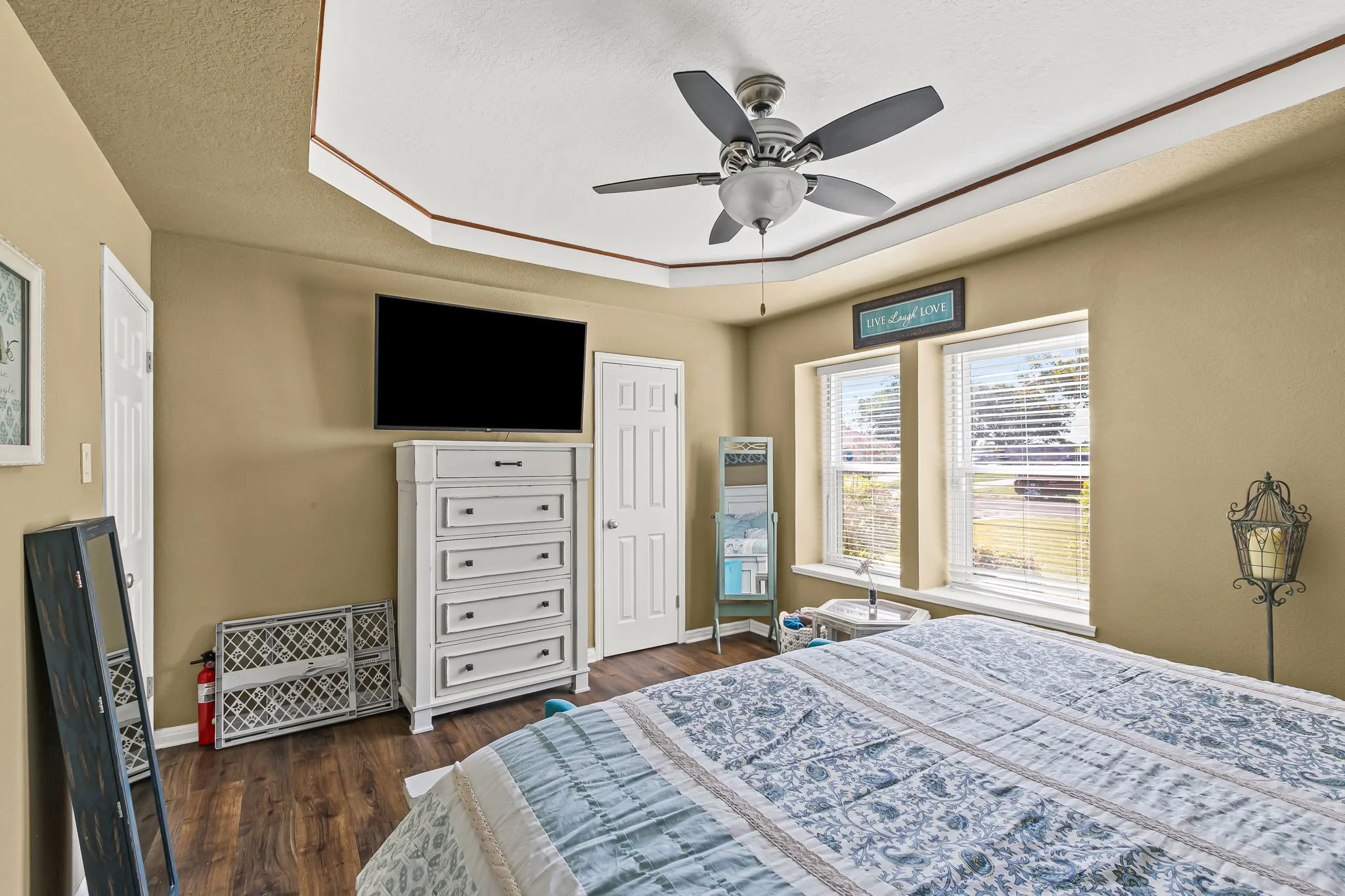 Bedroom with dark wood-style floors, a ceiling fan, a raised ceiling, and a textured ceiling