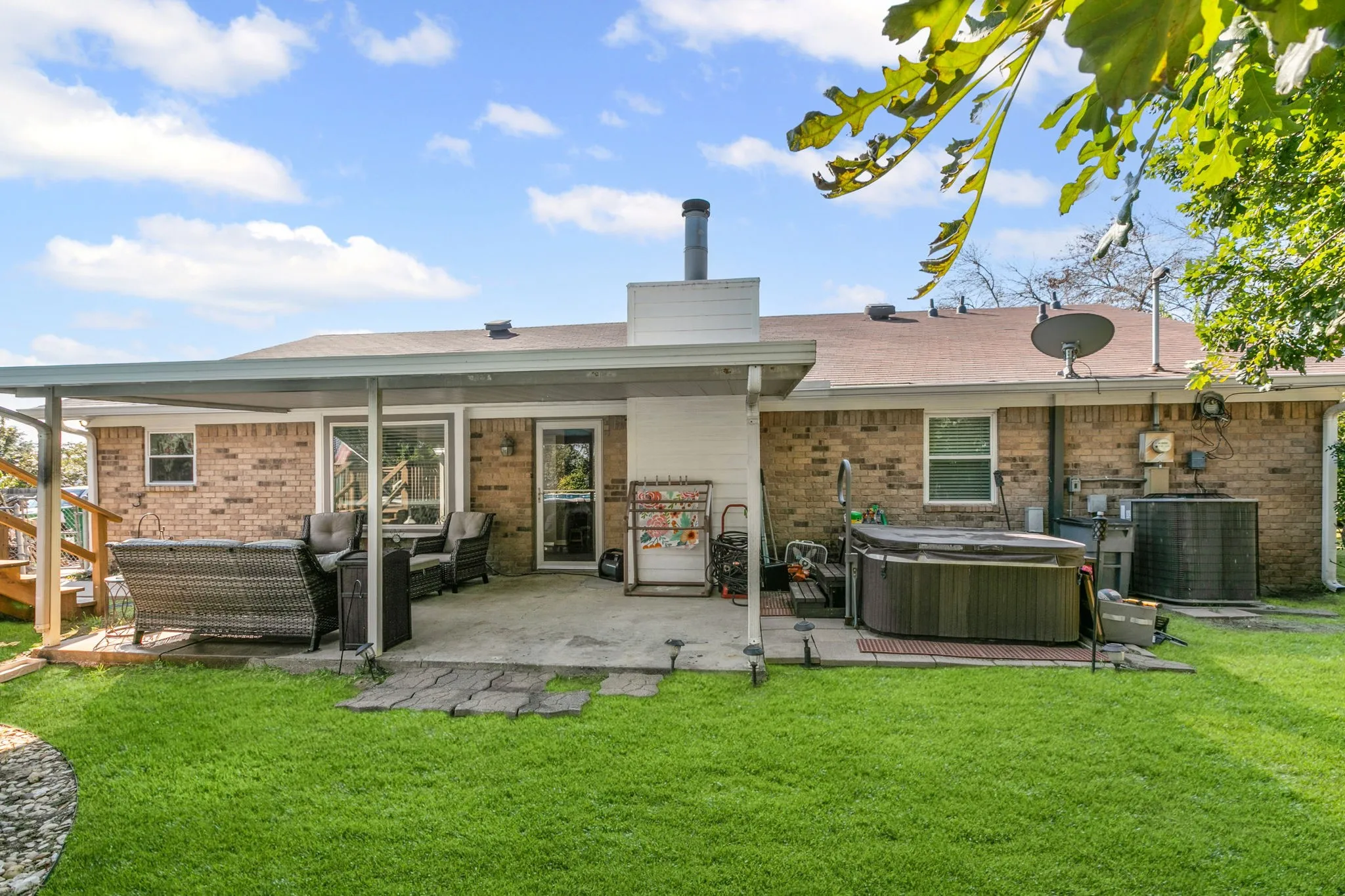 Rear view of house featuring a hot tub, an outdoor hangout area, a yard, and a patio