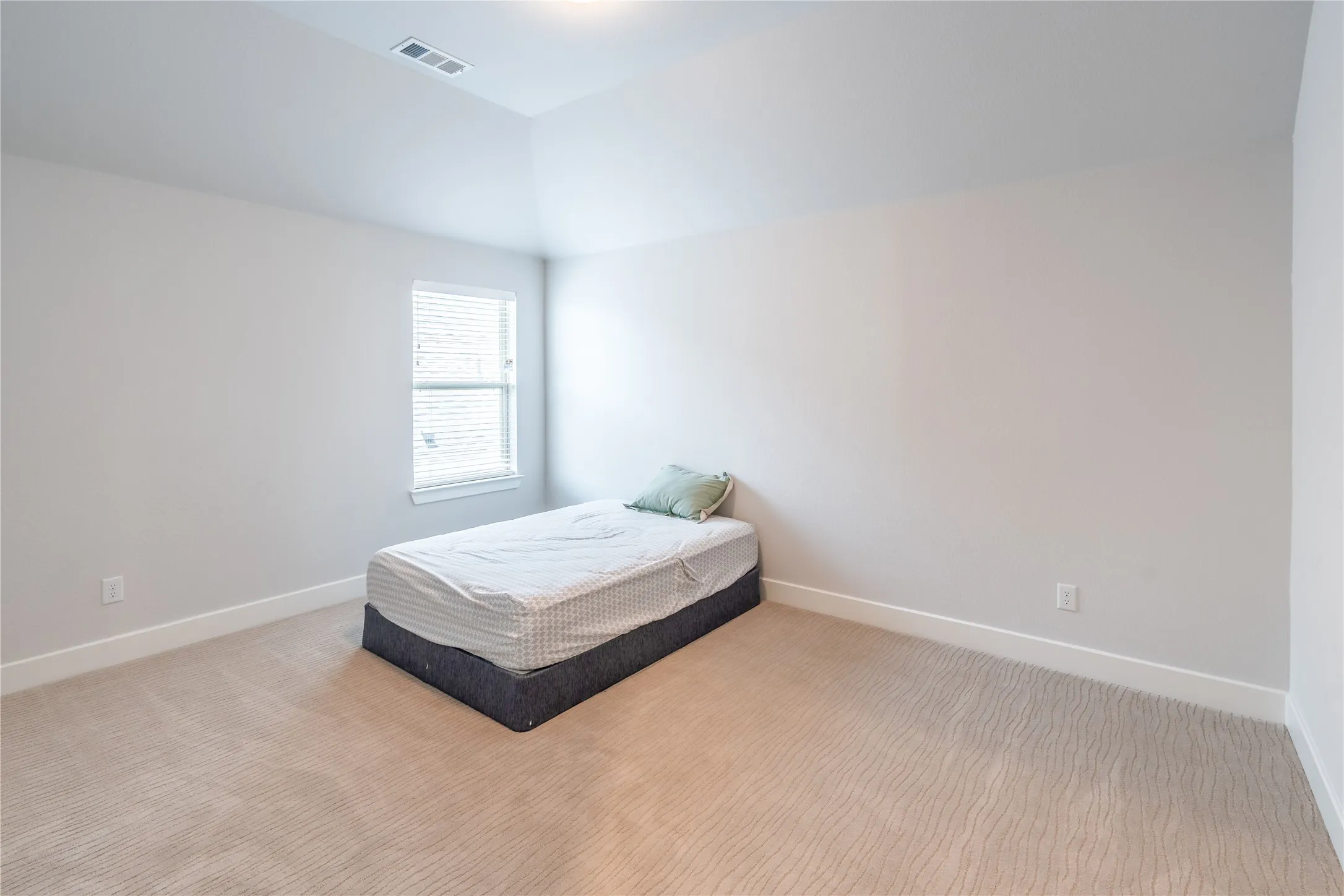 Carpeted bedroom featuring baseboards and vaulted ceiling