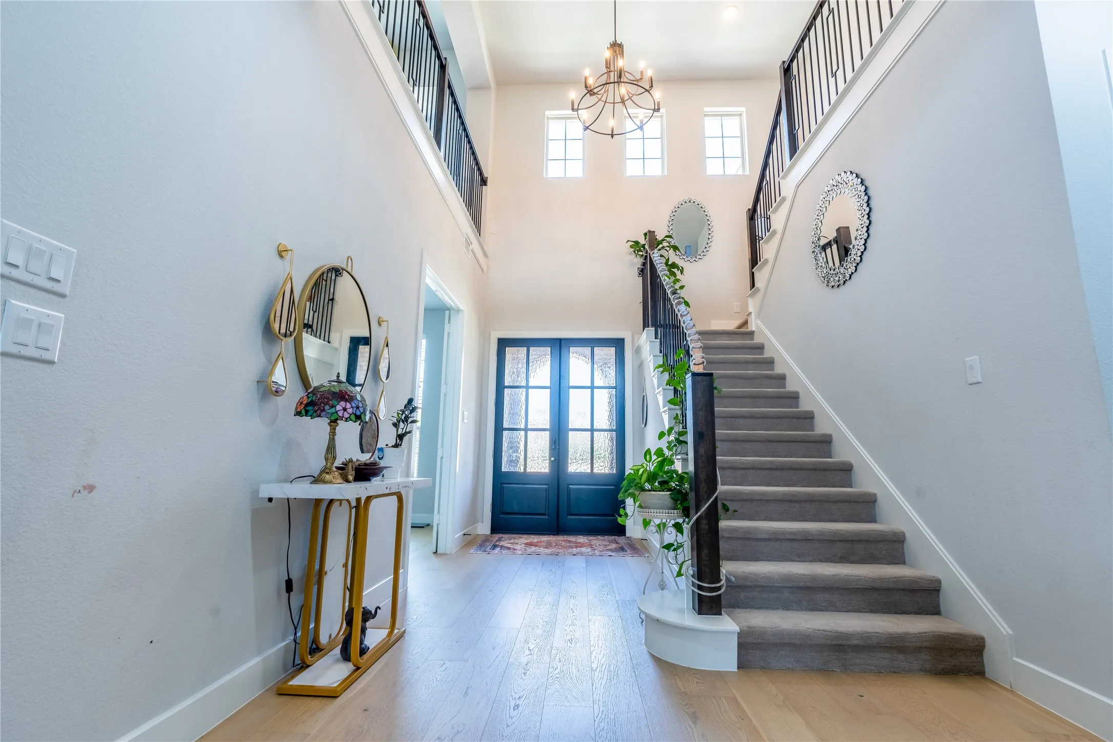 Entryway with hardwood / wood-style floors, plenty of natural light, french doors, a chandelier, and a towering ceiling