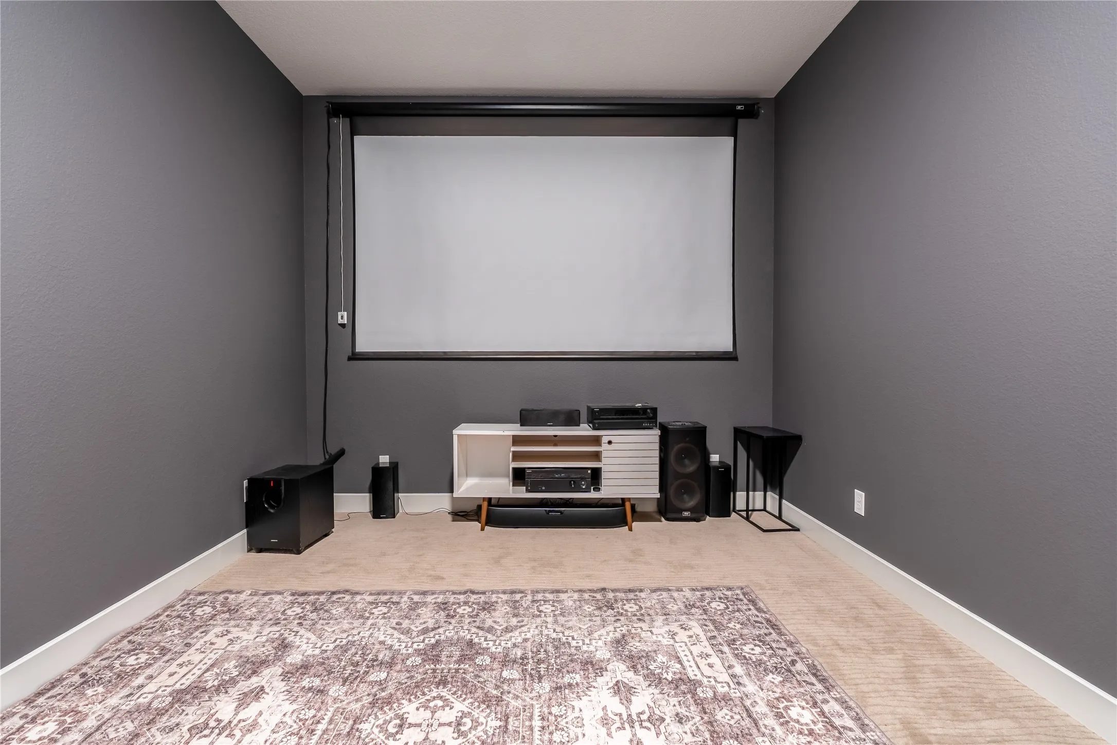 Carpeted home theater featuring baseboards
