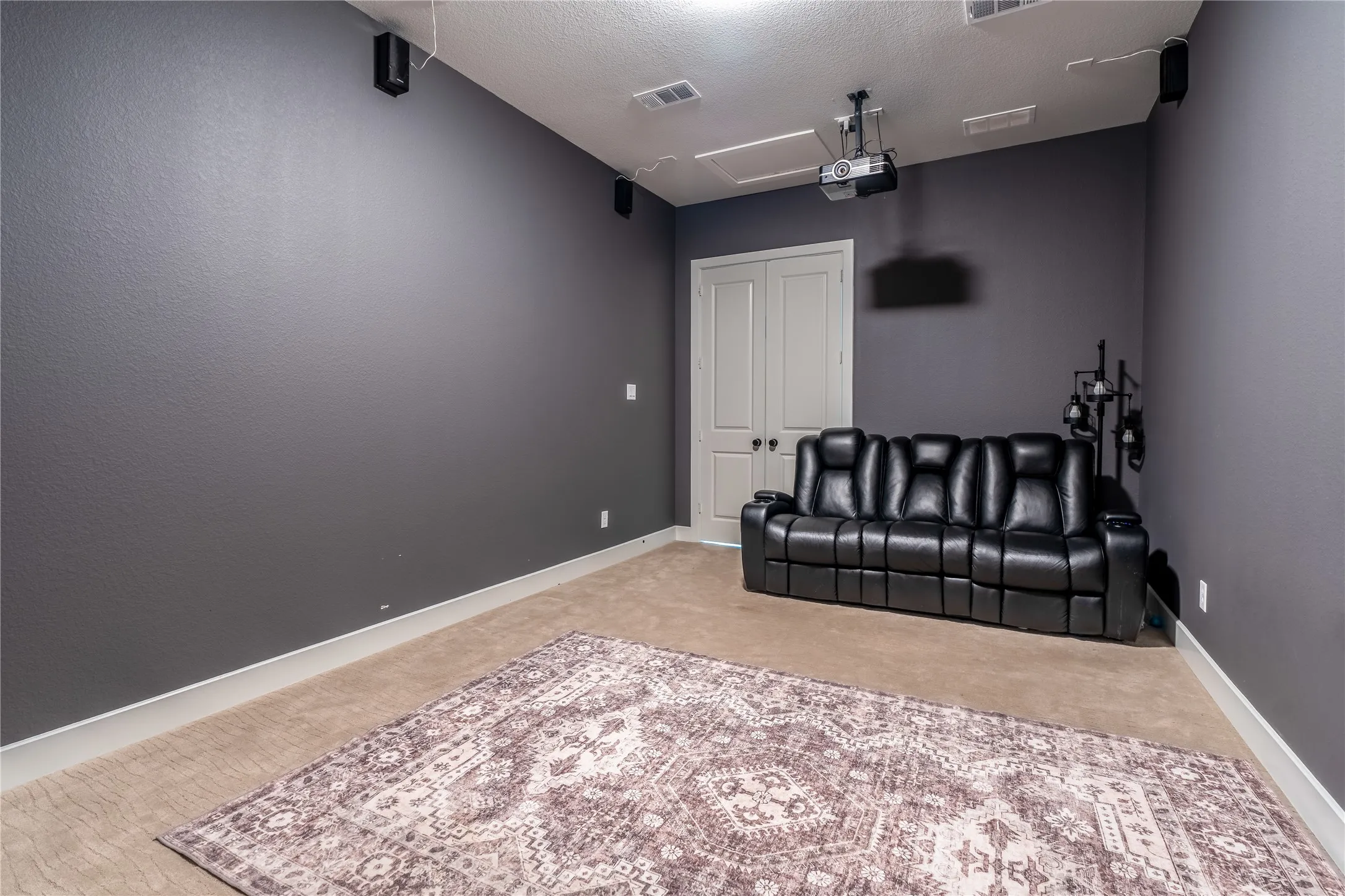 Cinema featuring a textured ceiling and light carpet
