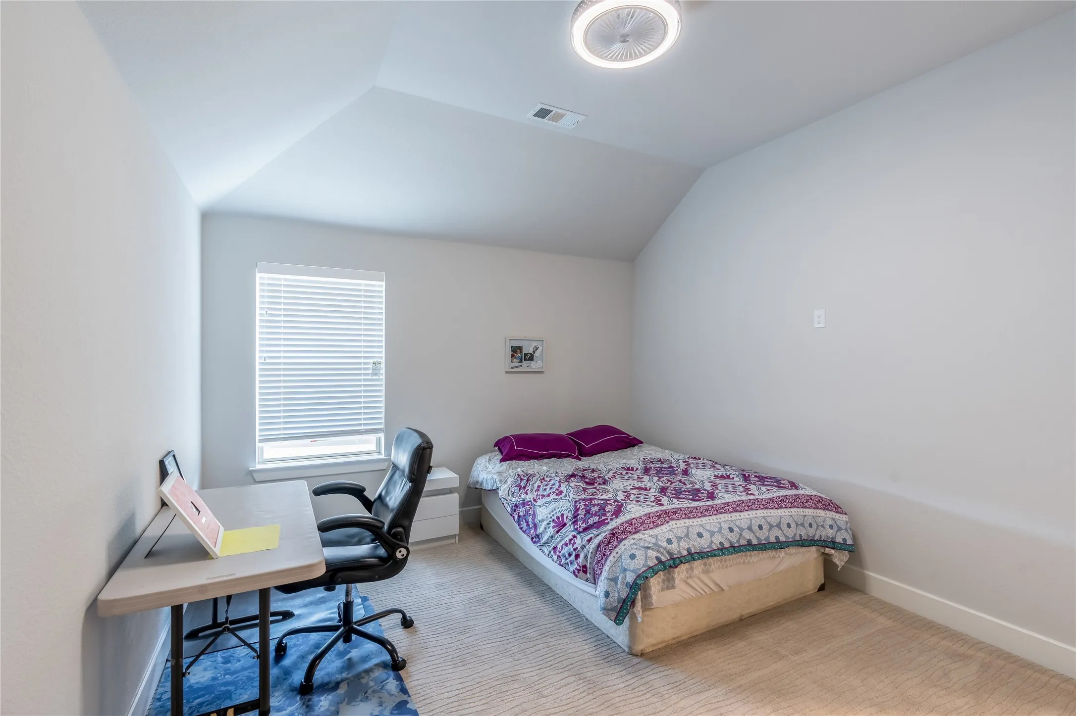 Carpeted bedroom featuring a desk and vaulted ceiling