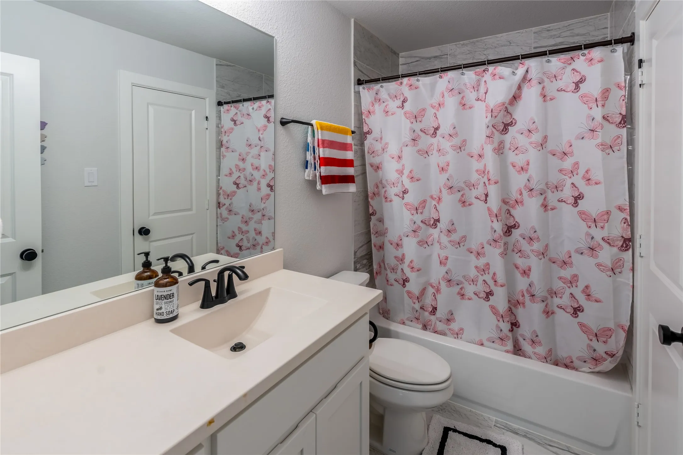 Bathroom featuring vanity, shower / bath combo, and a textured wall