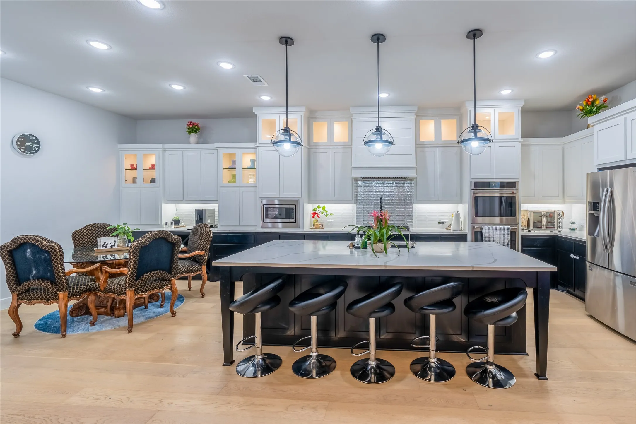 Kitchen featuring dark cabinets, decorative backsplash, glass insert cabinets, white cabinetry, and recessed lighting