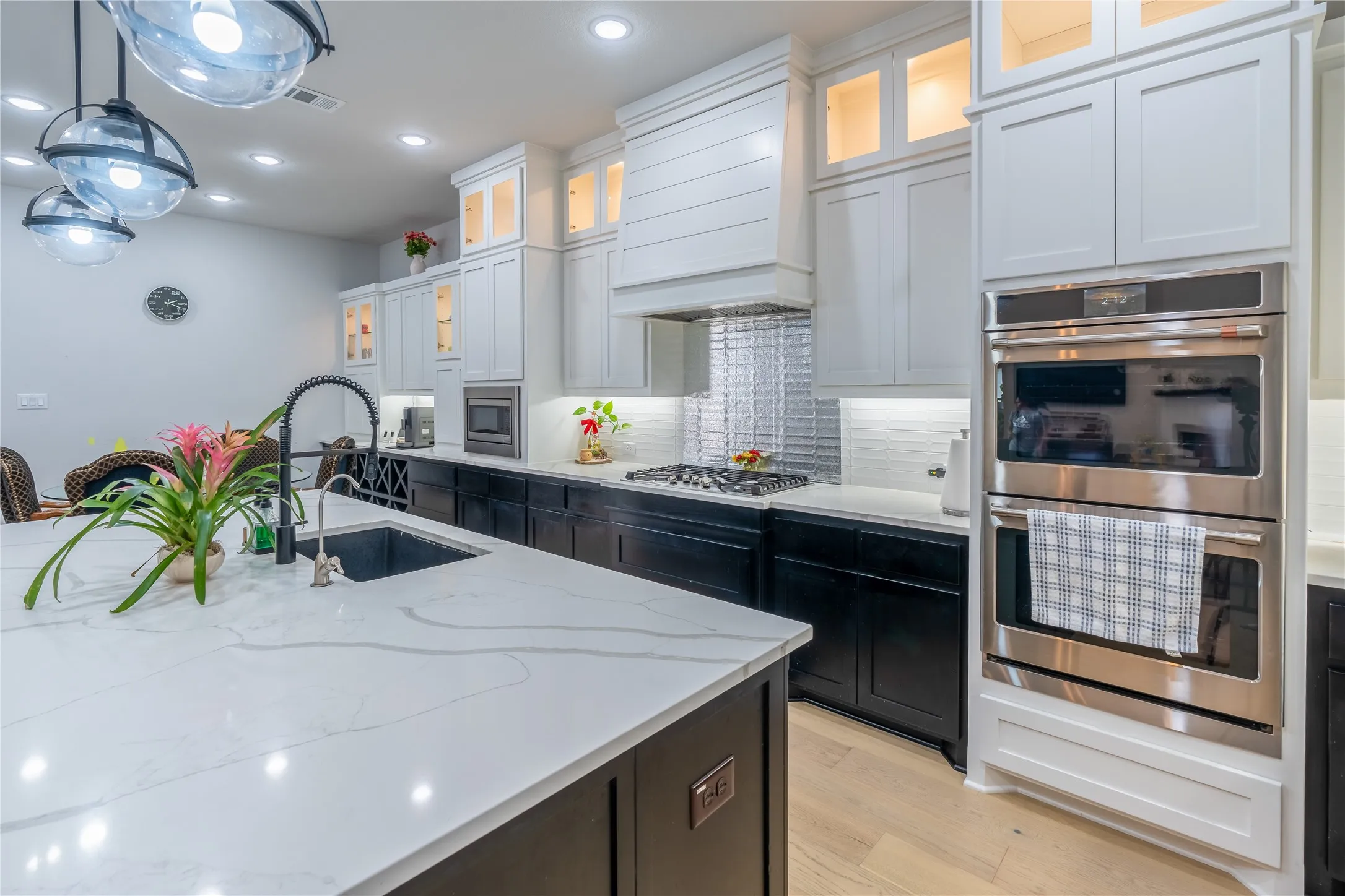 Kitchen with stainless steel appliances, glass insert cabinets, tasteful backsplash, dark cabinetry, and recessed lighting