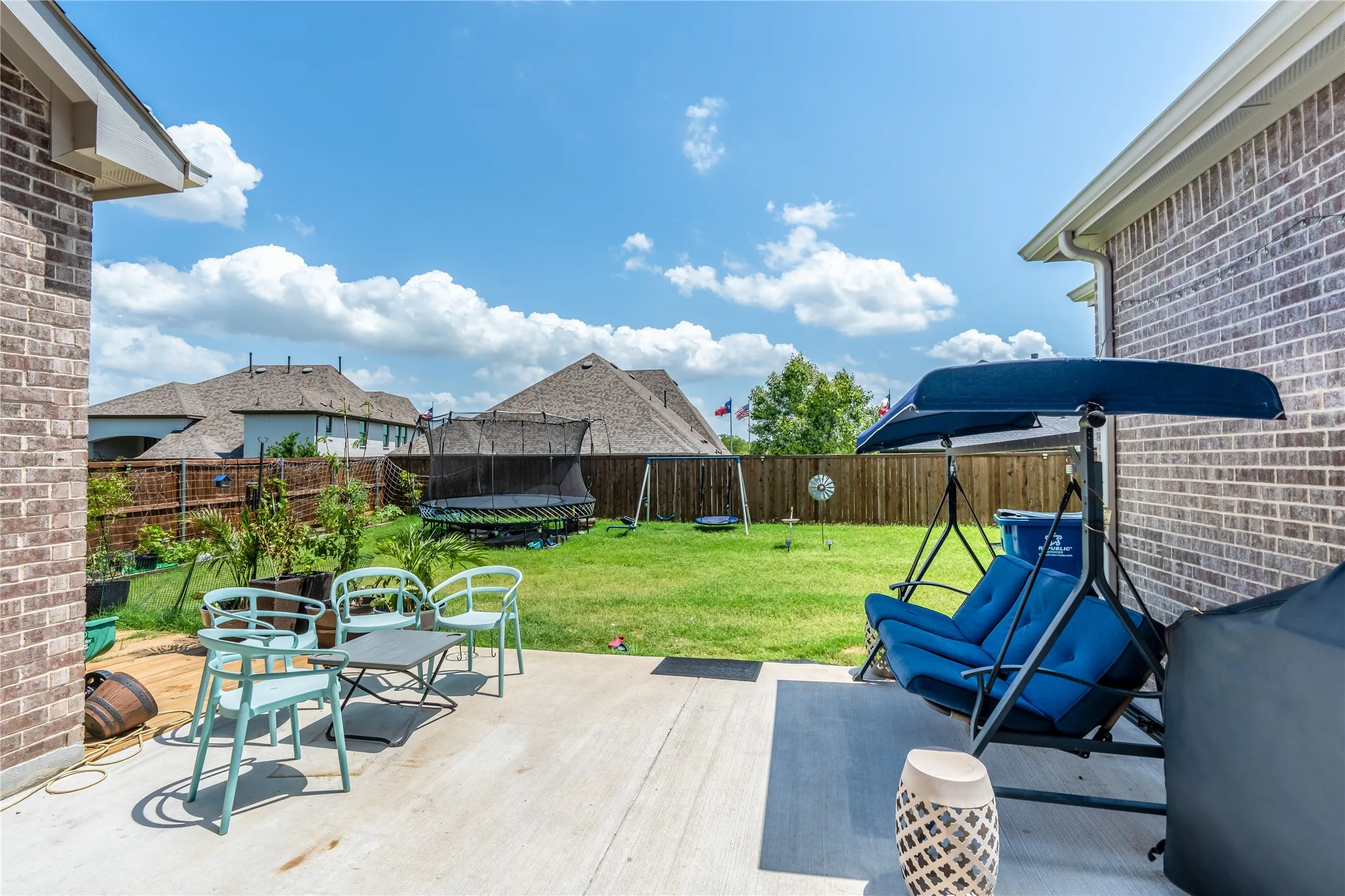 Wooden terrace with a fenced backyard, a trampoline, and a patio