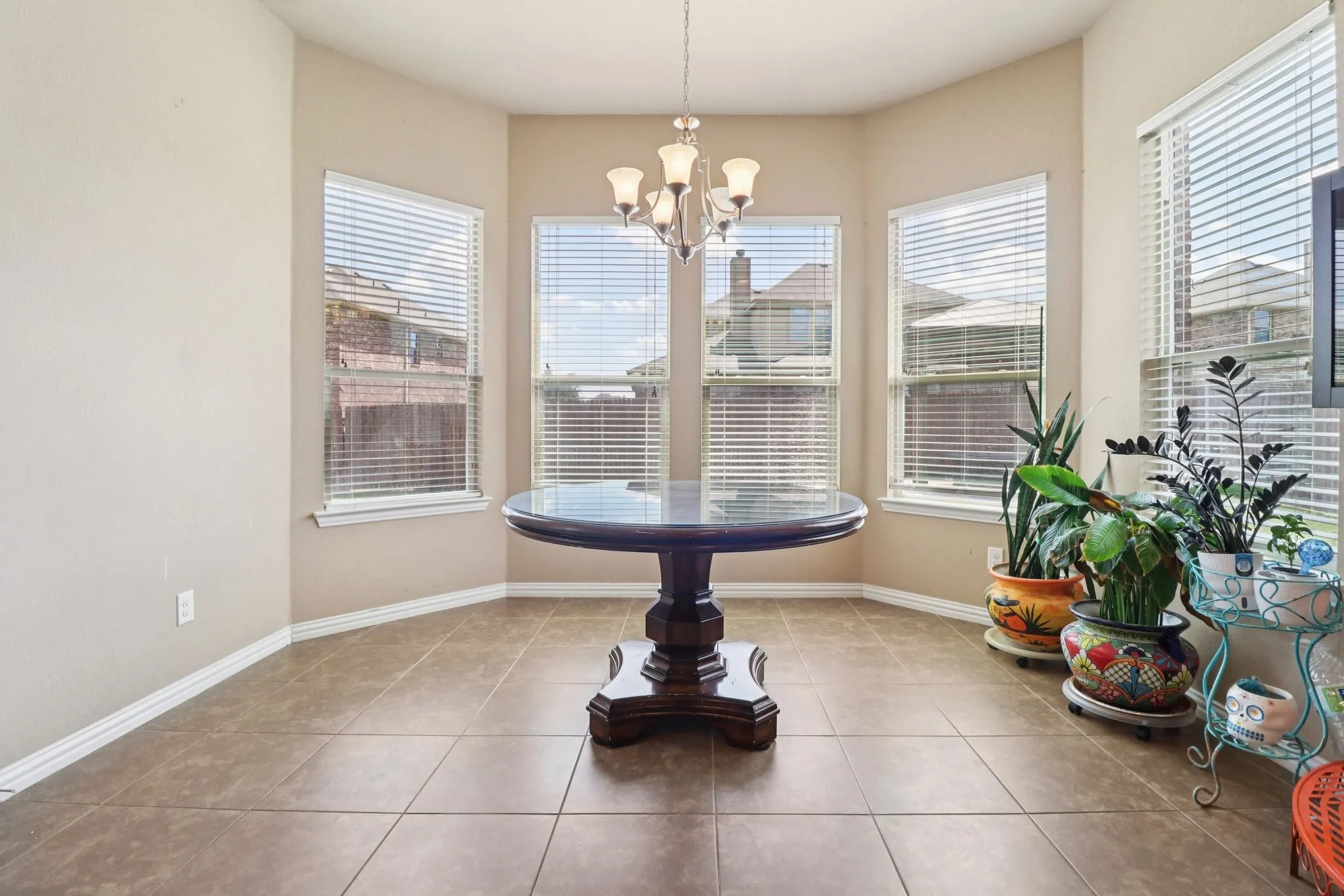 Tiled dining area featuring baseboards and a chandelier
