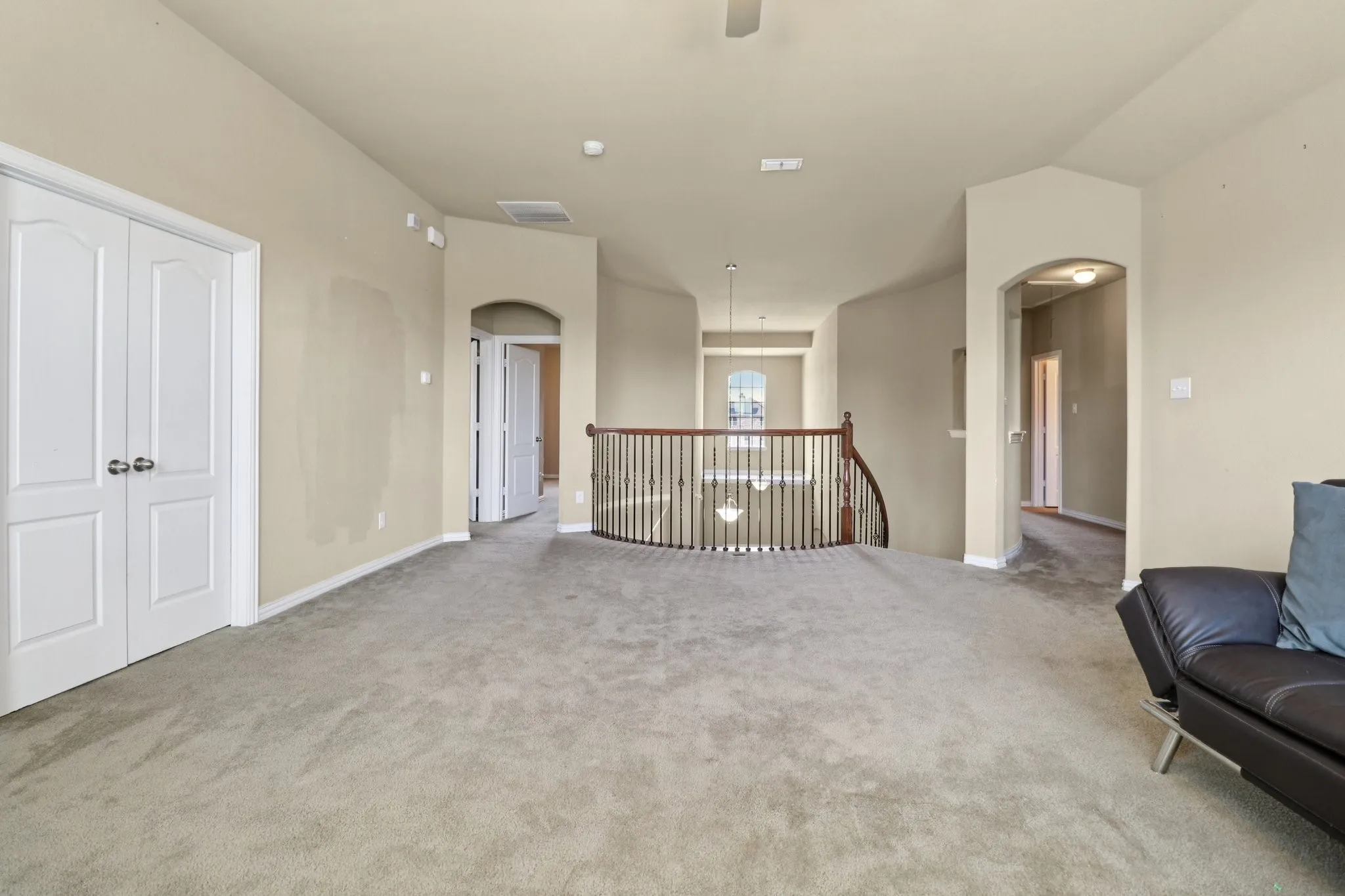 Unfurnished room with arched walkways, light colored carpet, and an upstairs landing