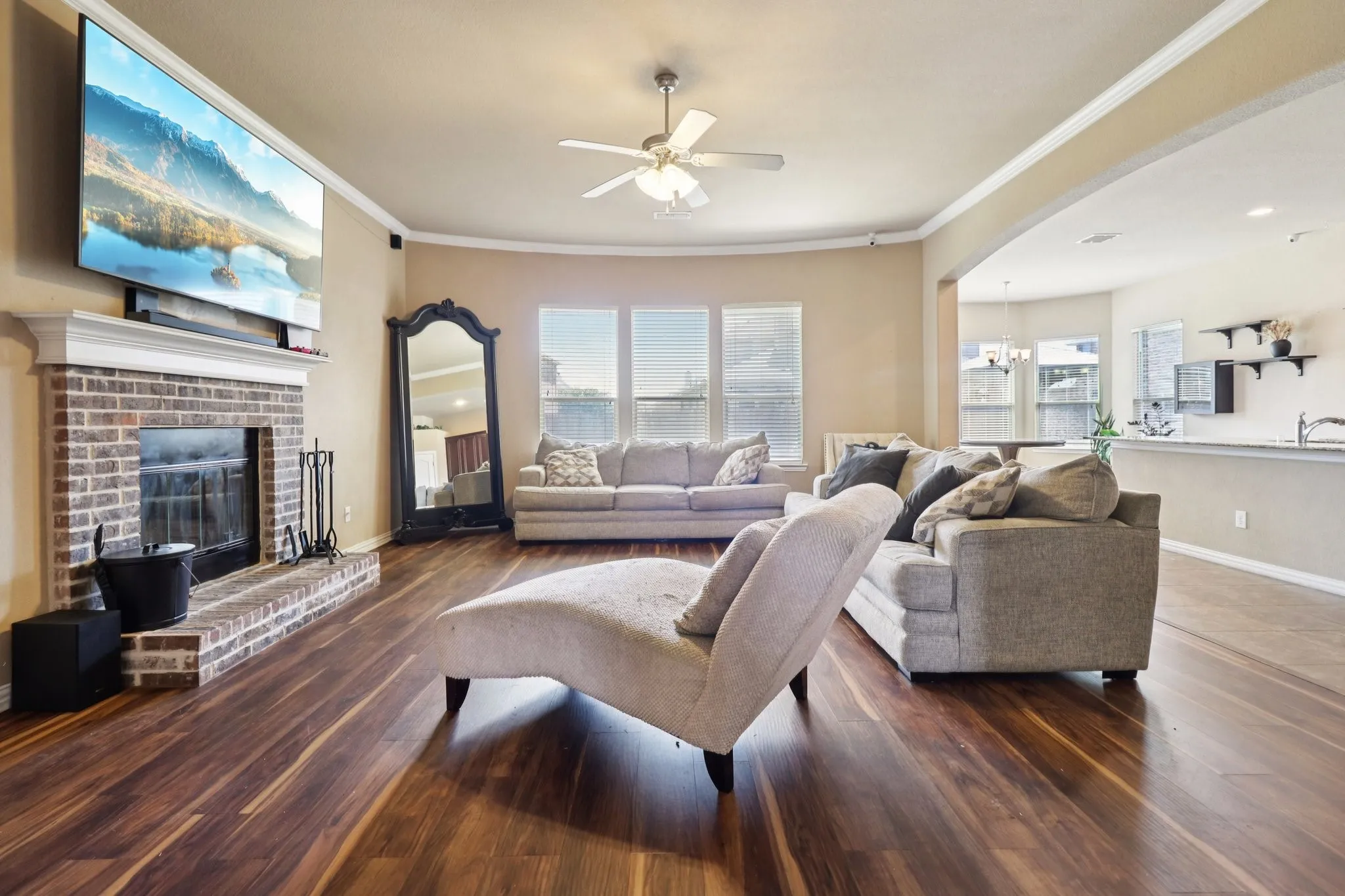 Living room featuring ornamental molding, a ceiling fan, a fireplace, dark wood-type flooring, and a chandelier
