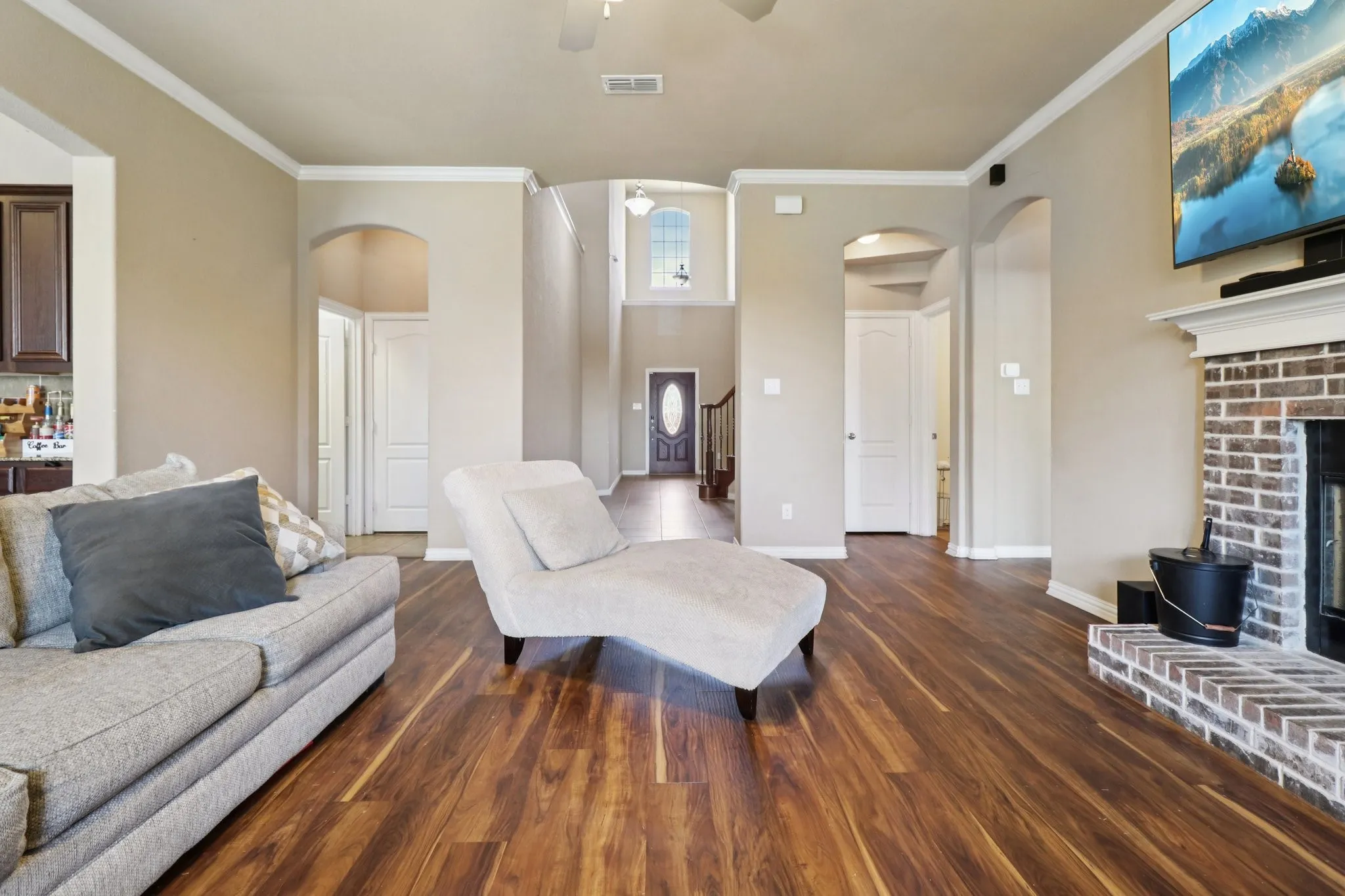 Living area featuring arched walkways, ornamental molding, dark wood-type flooring, ceiling fan, and a fireplace