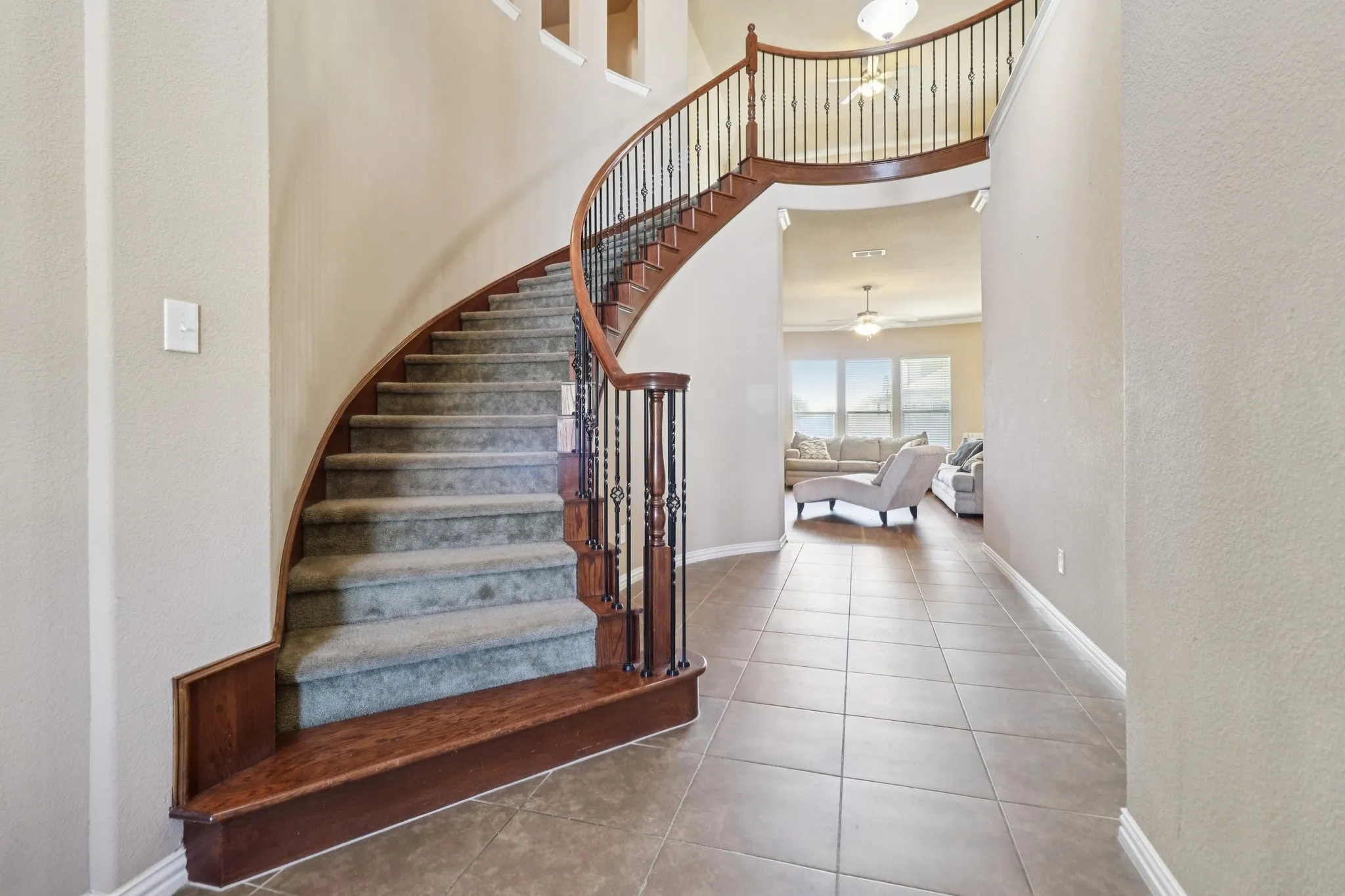 Stairway featuring tile patterned floors, a textured wall, and a high ceiling