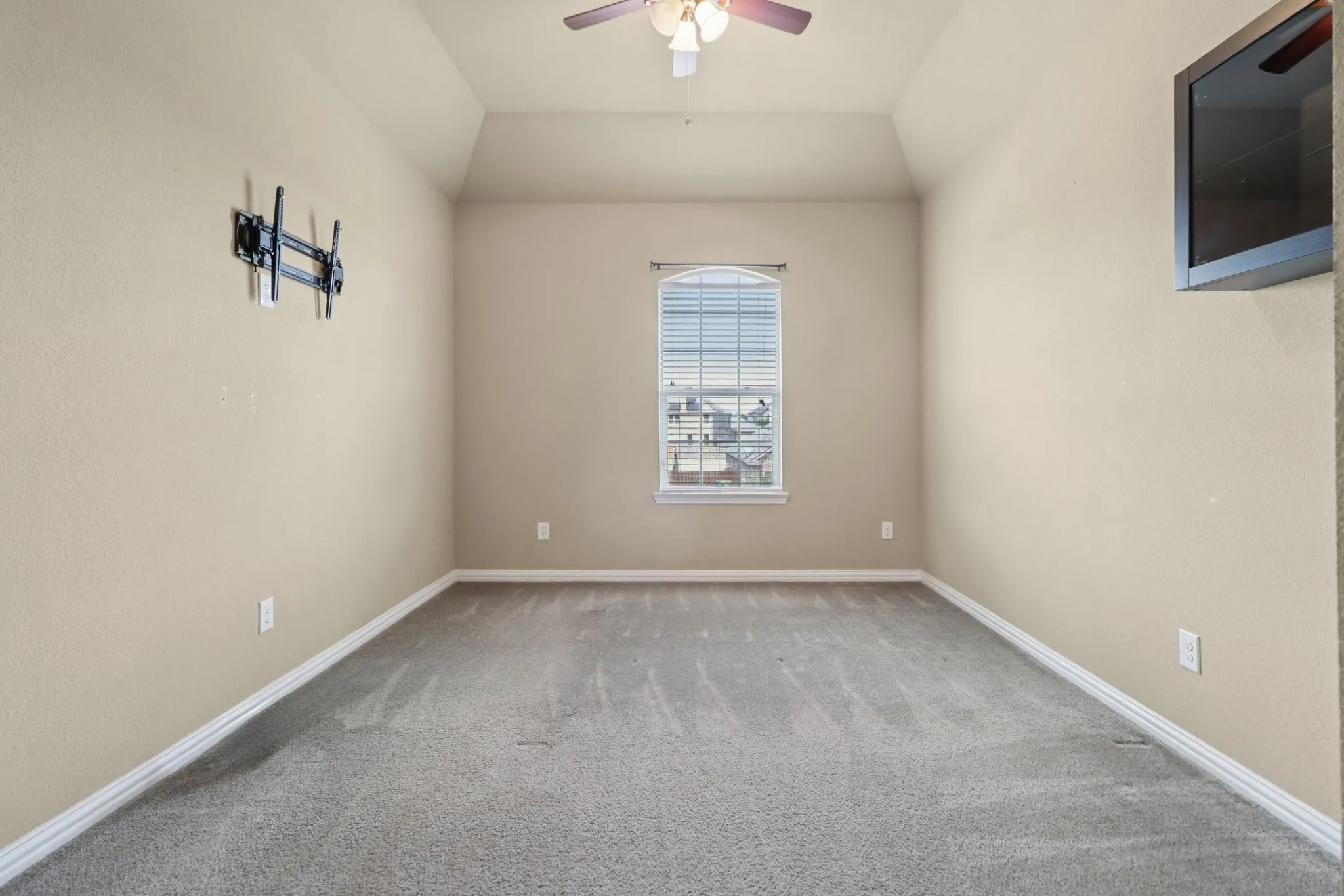 Carpeted empty room with a ceiling fan and lofted ceiling