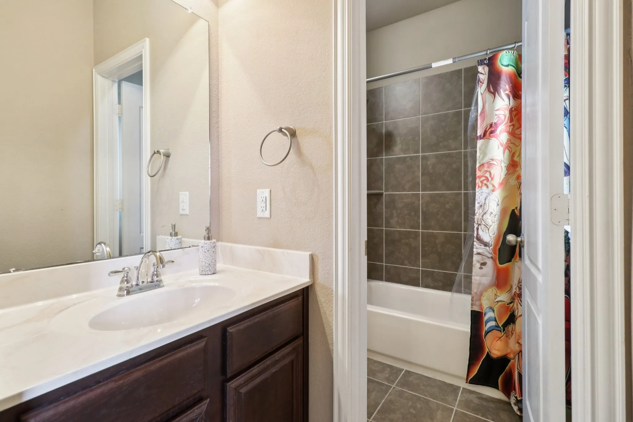 Full bathroom featuring shower / bath combo, vanity, dark tile patterned flooring, and a textured wall