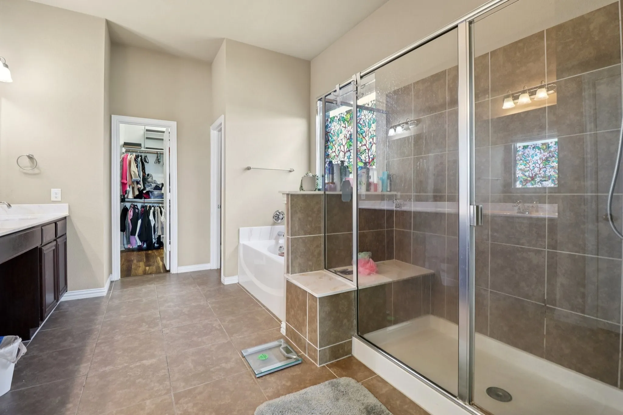 Full bathroom with vanity, a spacious closet, a garden tub, light tile patterned flooring, and a stall shower
