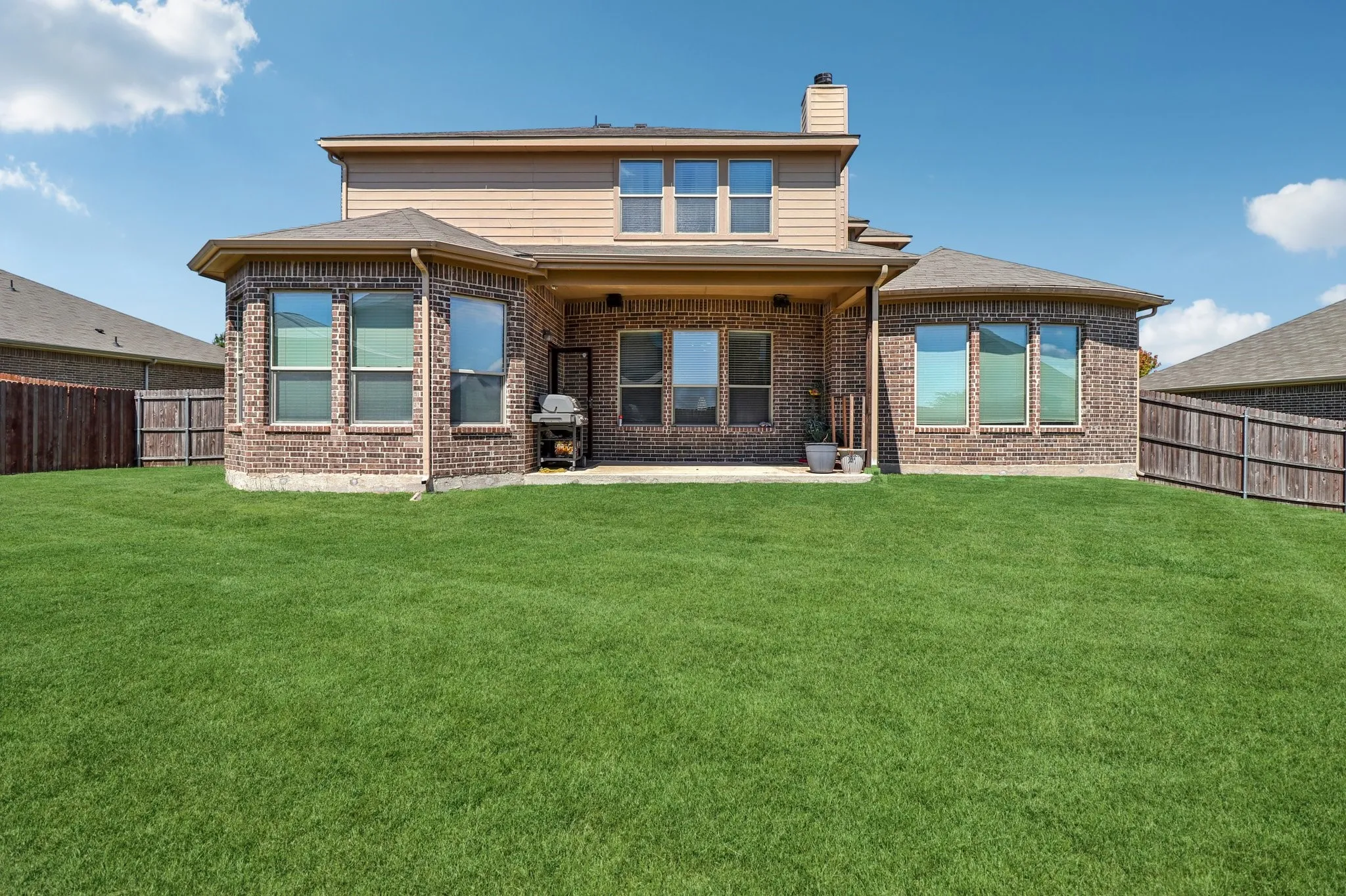 Back of house featuring a patio, a chimney, a fenced backyard, and brick siding