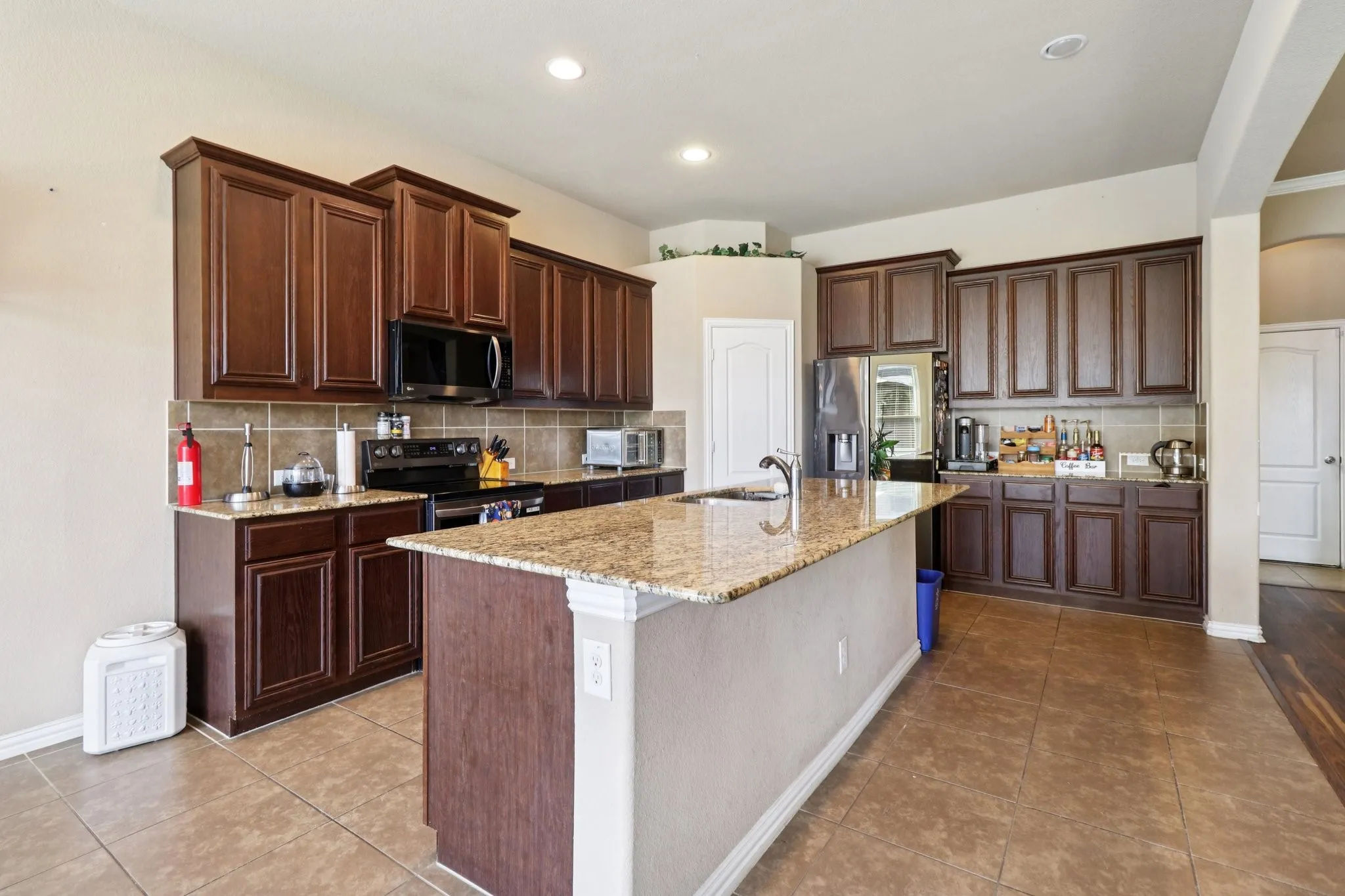 Kitchen featuring decorative backsplash, light stone countertops, light tile patterned floors, appliances with stainless steel finishes, and recessed lighting