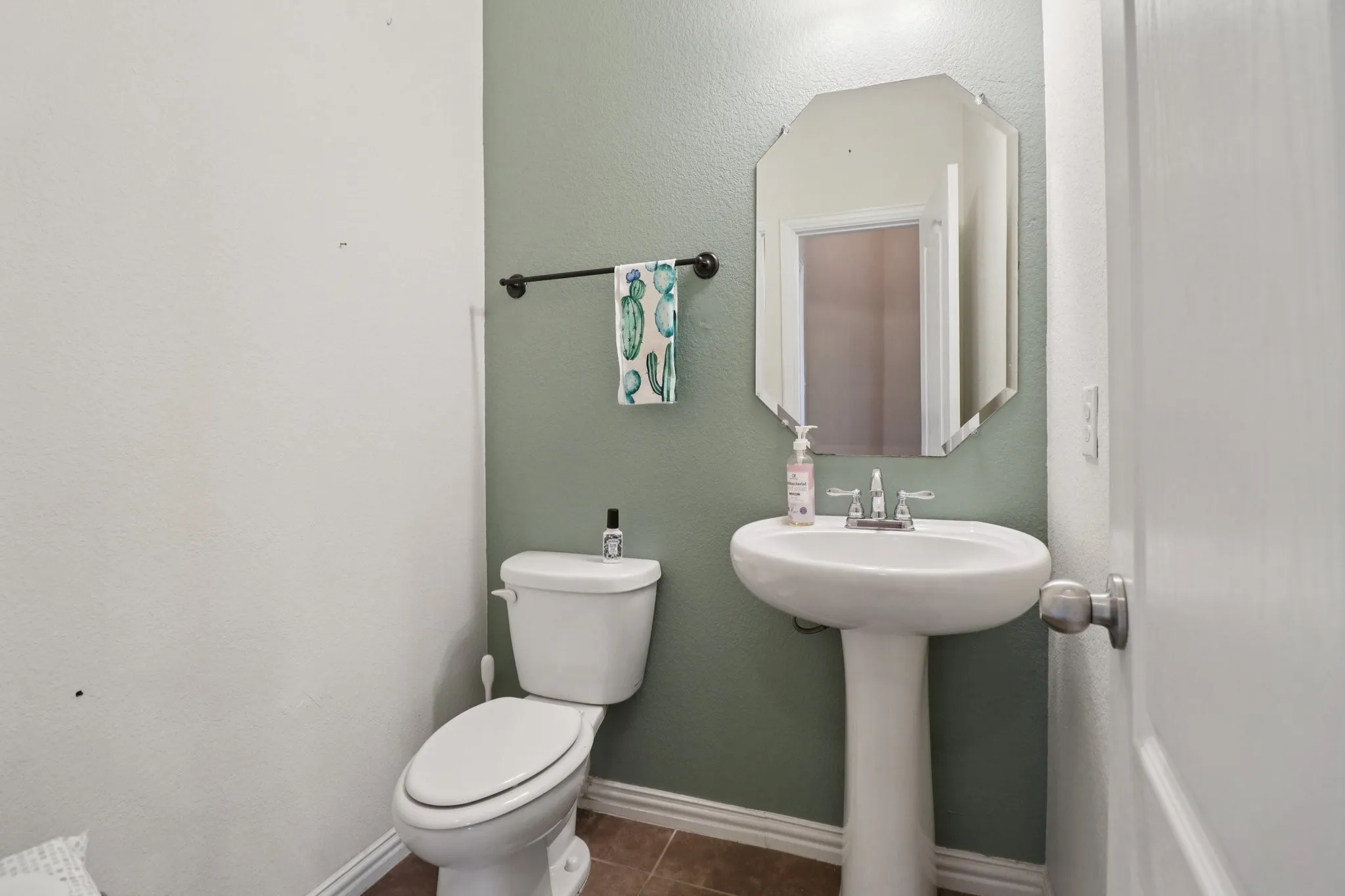 Half bathroom featuring a textured wall and dark tile patterned floors