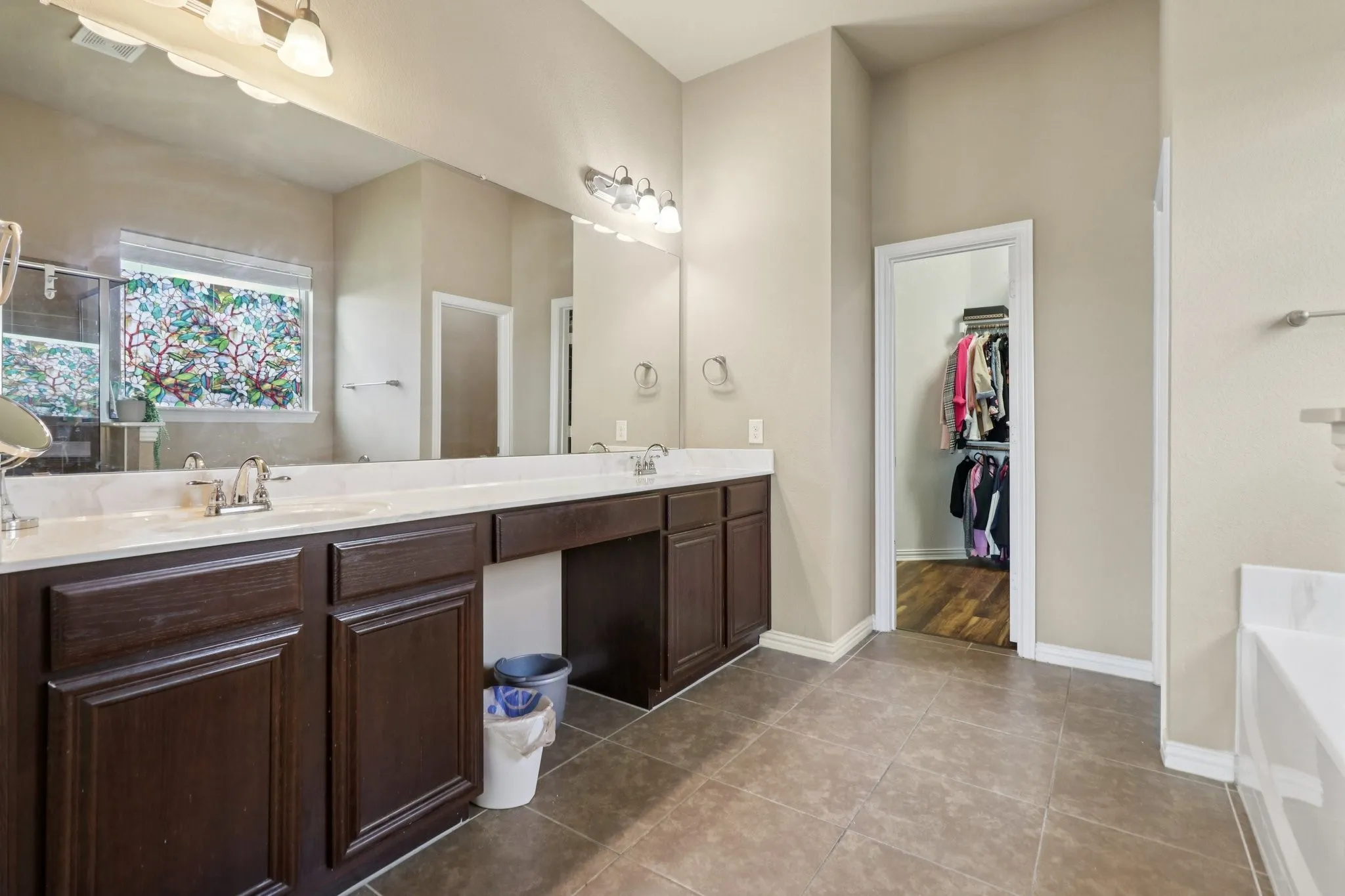Full bath featuring dark tile patterned flooring, double vanity, a bath, and a spacious closet