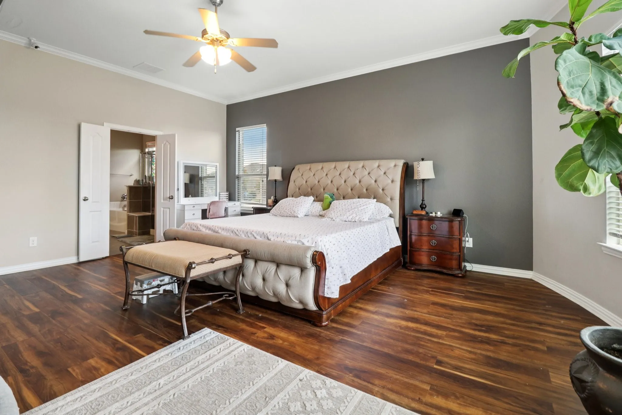 Bedroom with ornamental molding, dark wood-style floors, and a ceiling fan