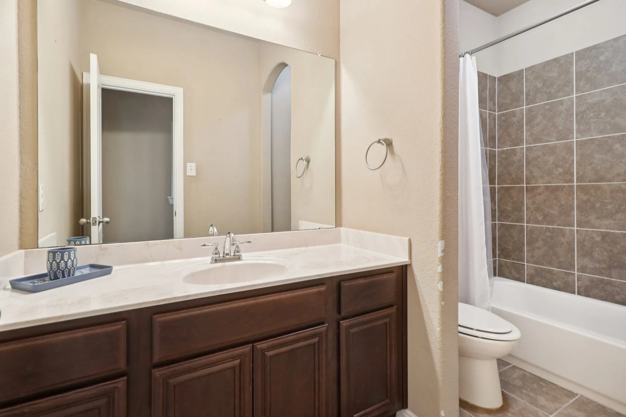 Bathroom featuring a textured wall, vanity, shower / tub combo with curtain, and tile patterned flooring