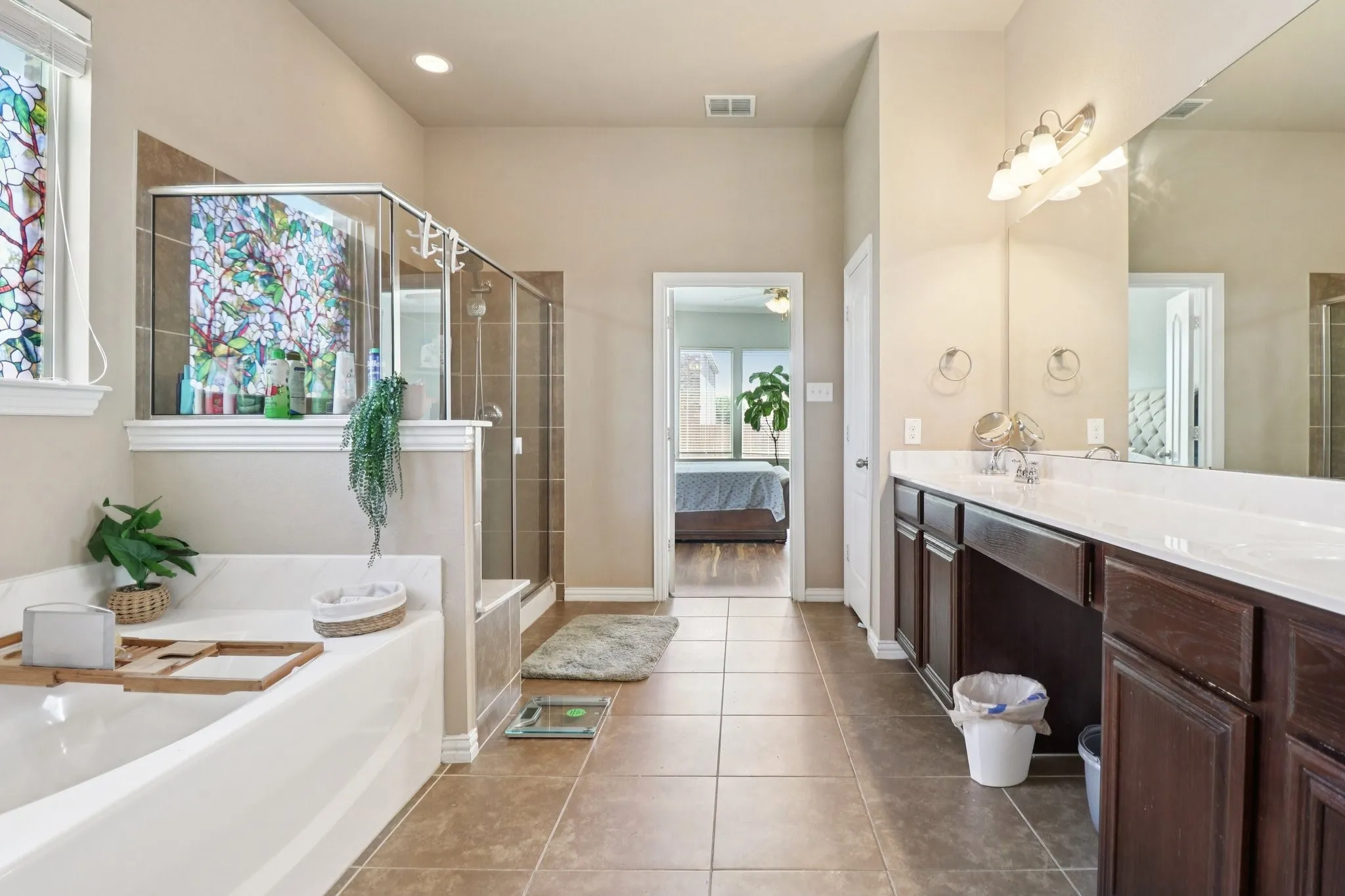 Ensuite bathroom featuring double vanity, a garden tub, light tile patterned floors, and a shower stall