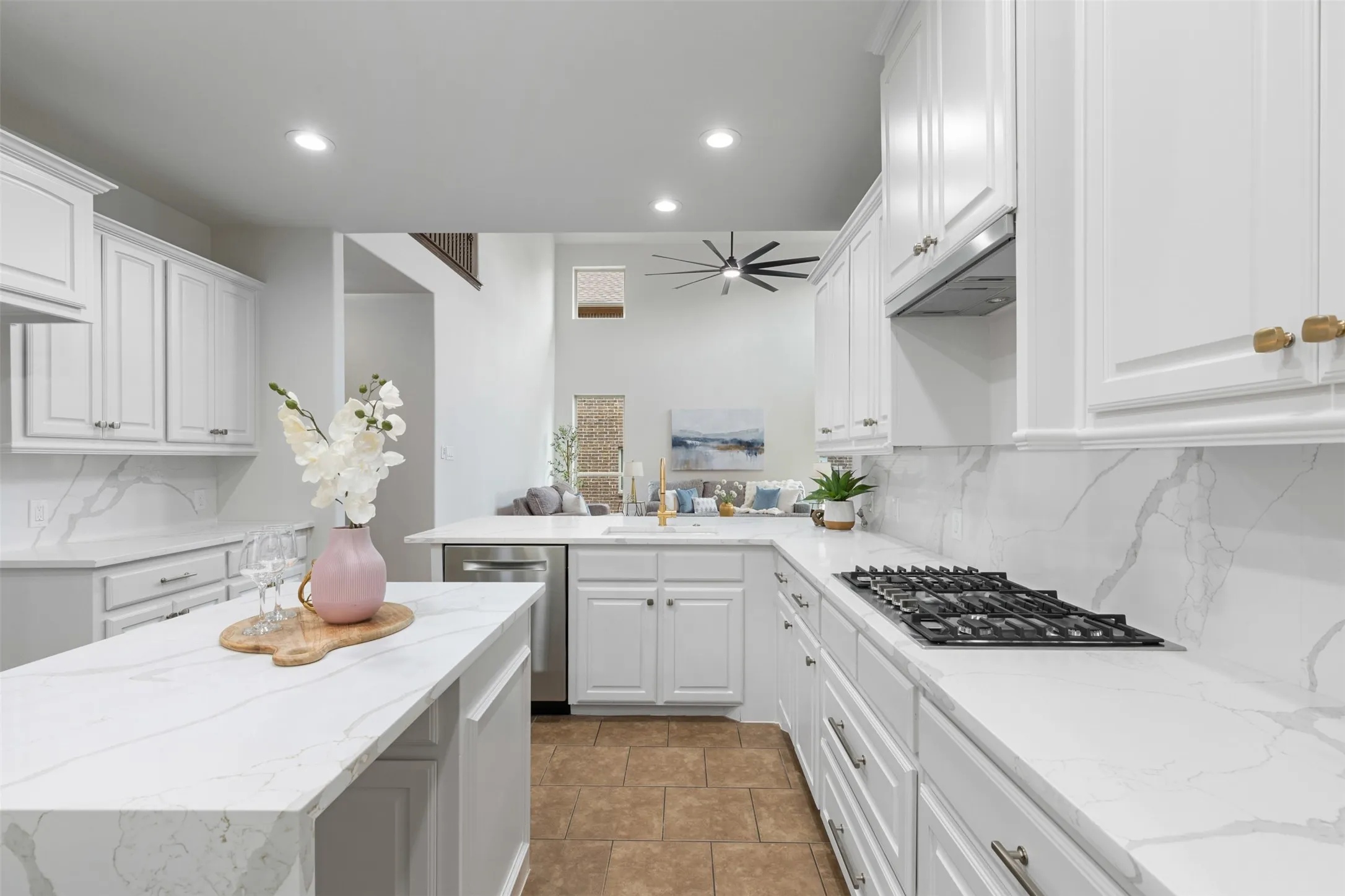 Kitchen with under cabinet range hood, appliances with stainless steel finishes, white cabinets, backsplash, and a sink