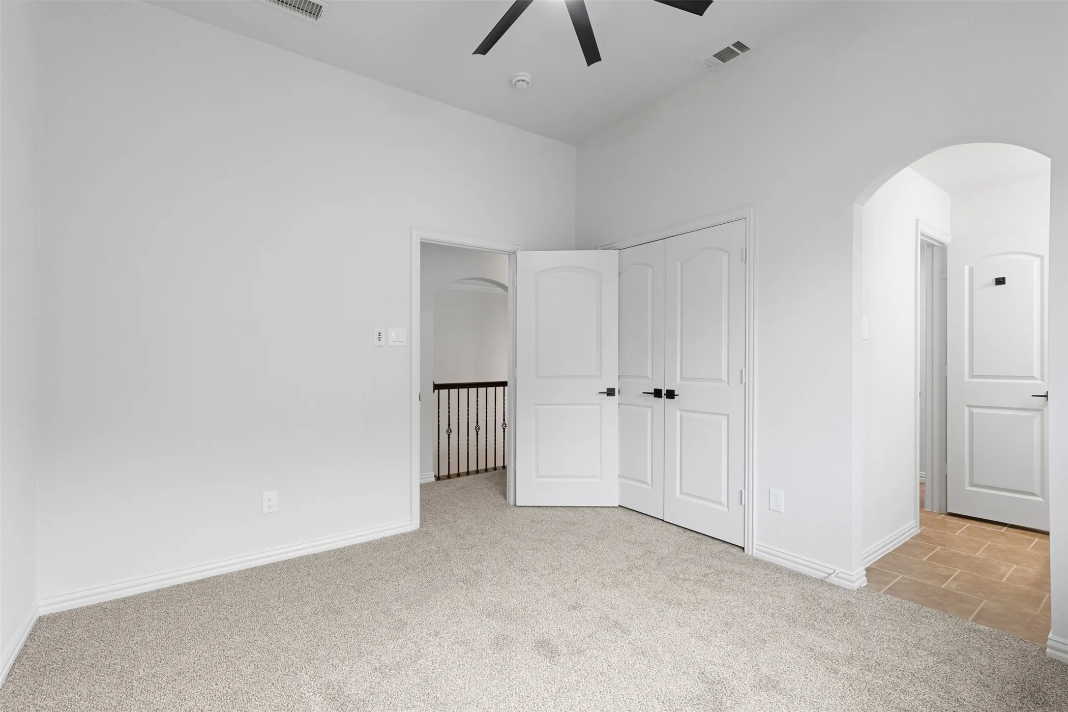 Unfurnished bedroom with arched walkways, a closet, carpet flooring, baseboards, and visible vents