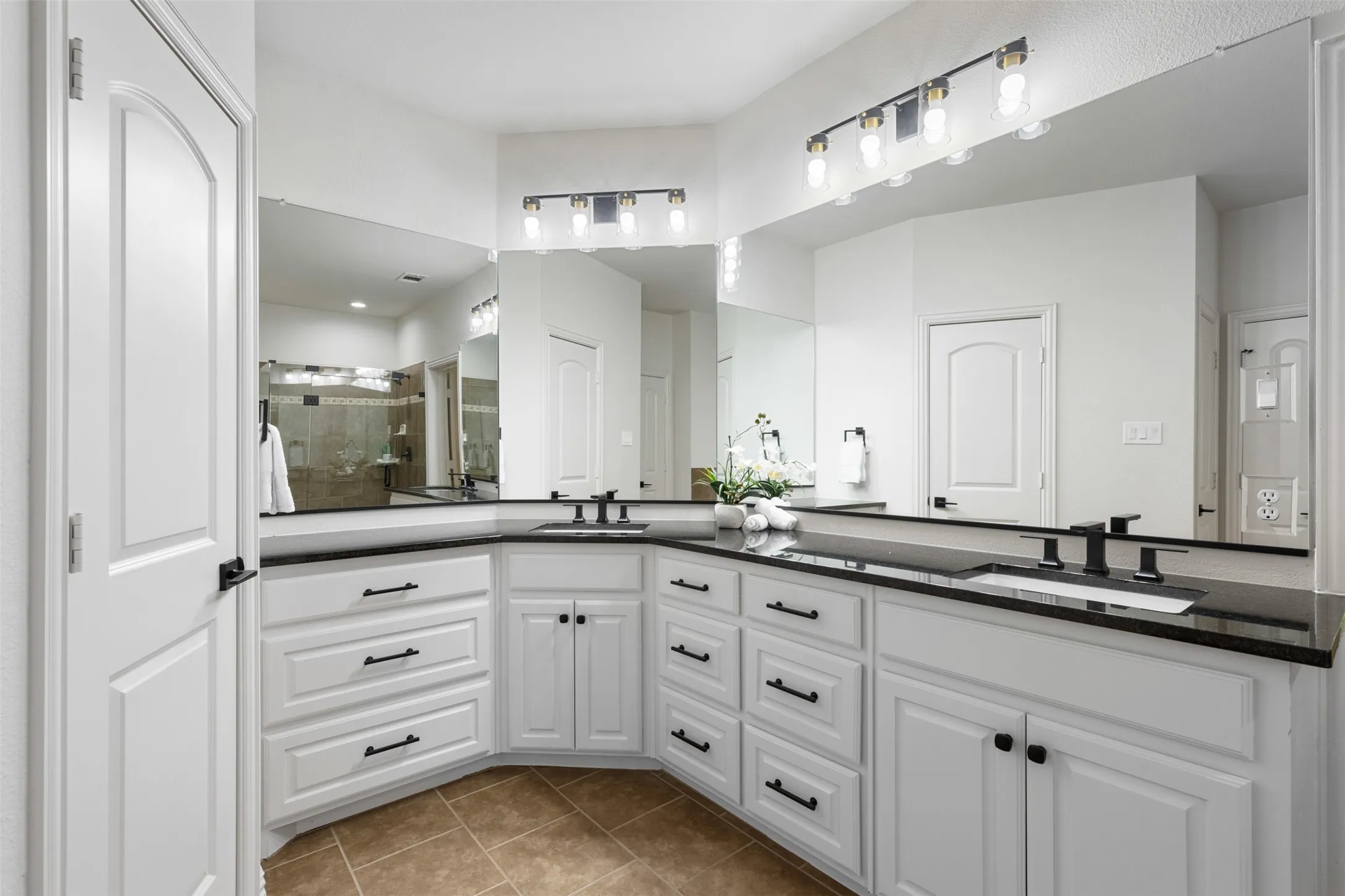 Bathroom with double vanity, a shower stall, tile patterned flooring, and a sink