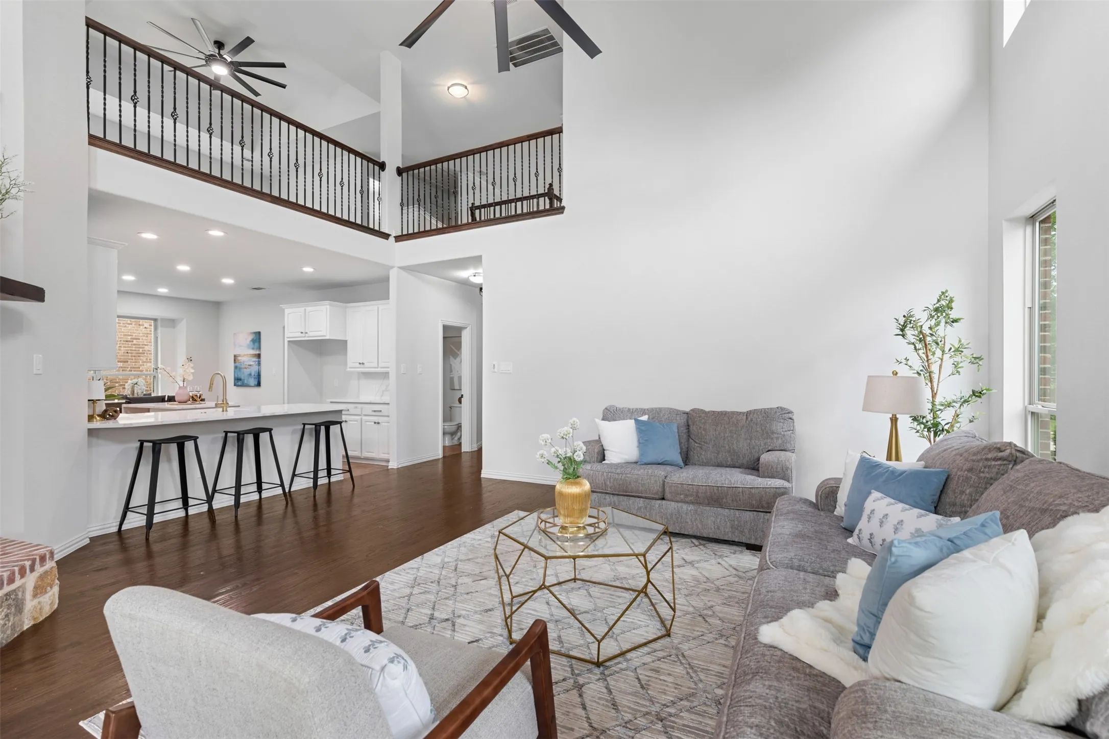 Living area with a towering ceiling, visible vents, a ceiling fan, and dark wood-style floors
