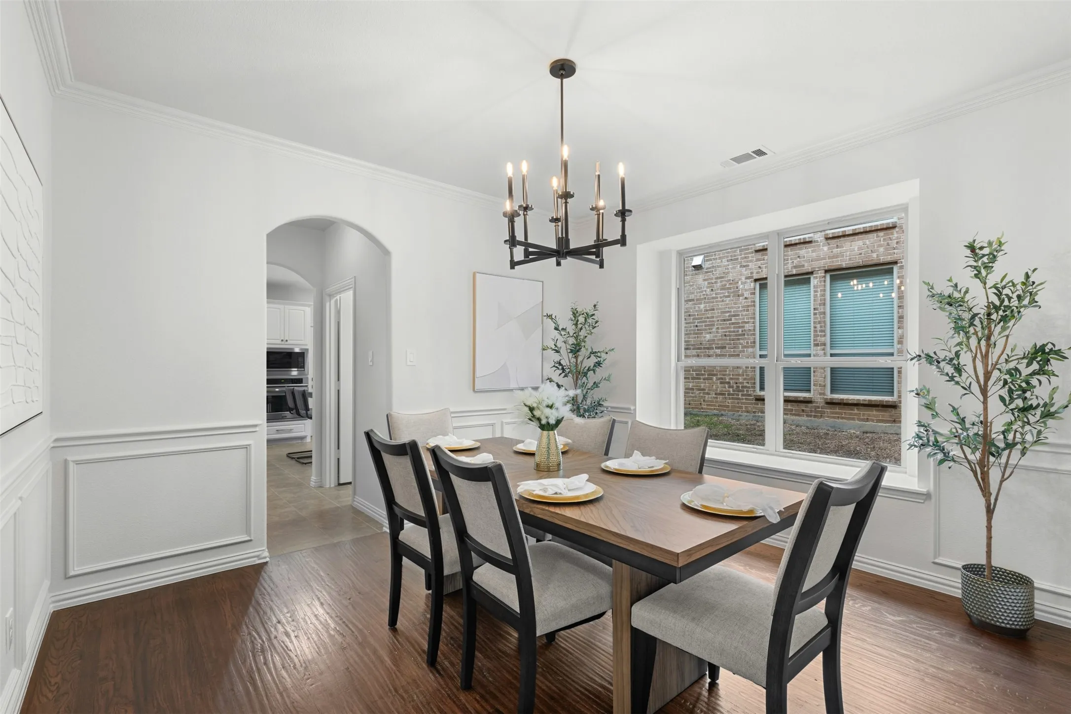Dining room with visible vents, arched walkways, dark wood-style flooring, ornamental molding, and a notable chandelier