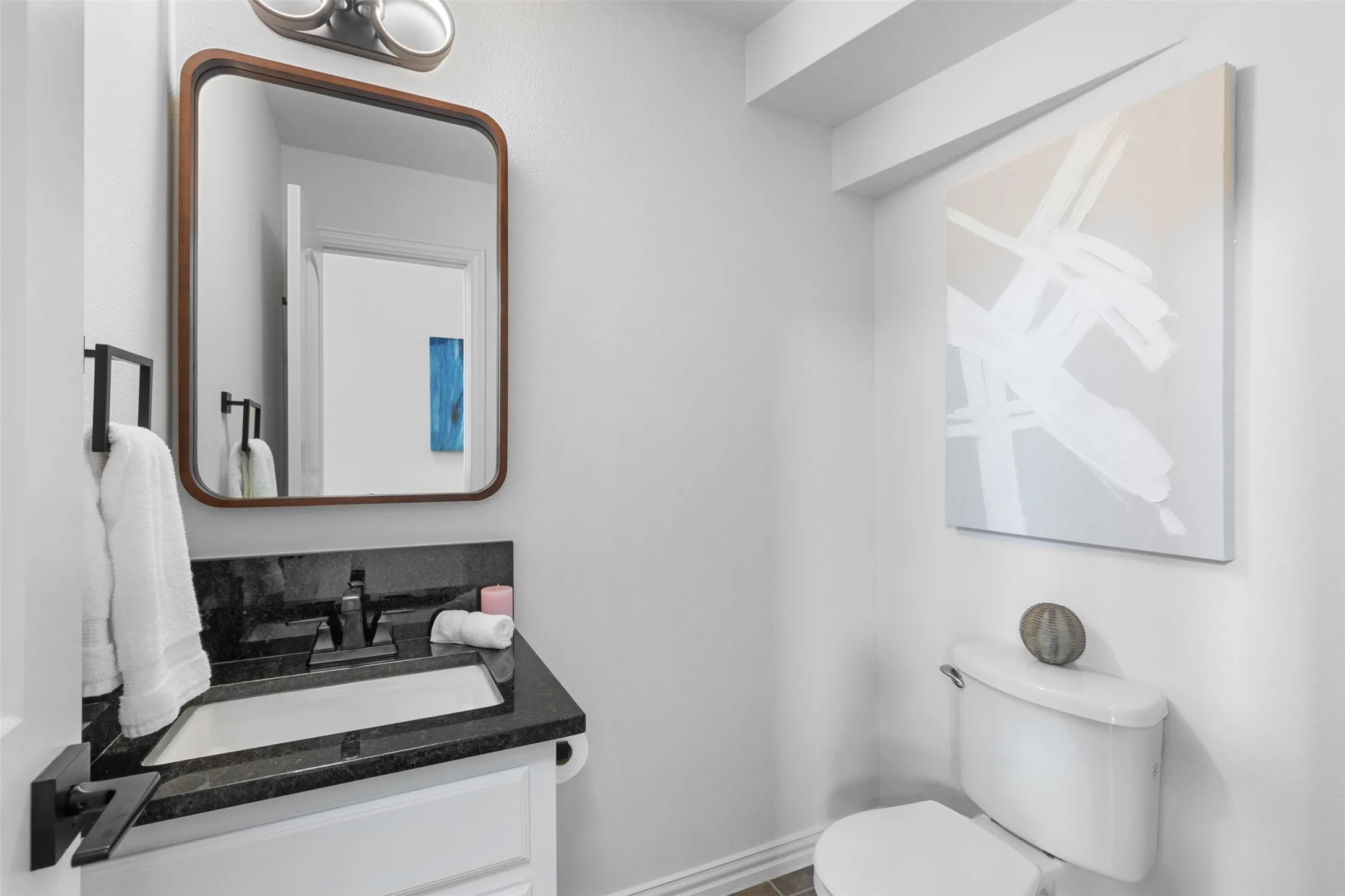 Half bathroom with vanity, toilet, and baseboards