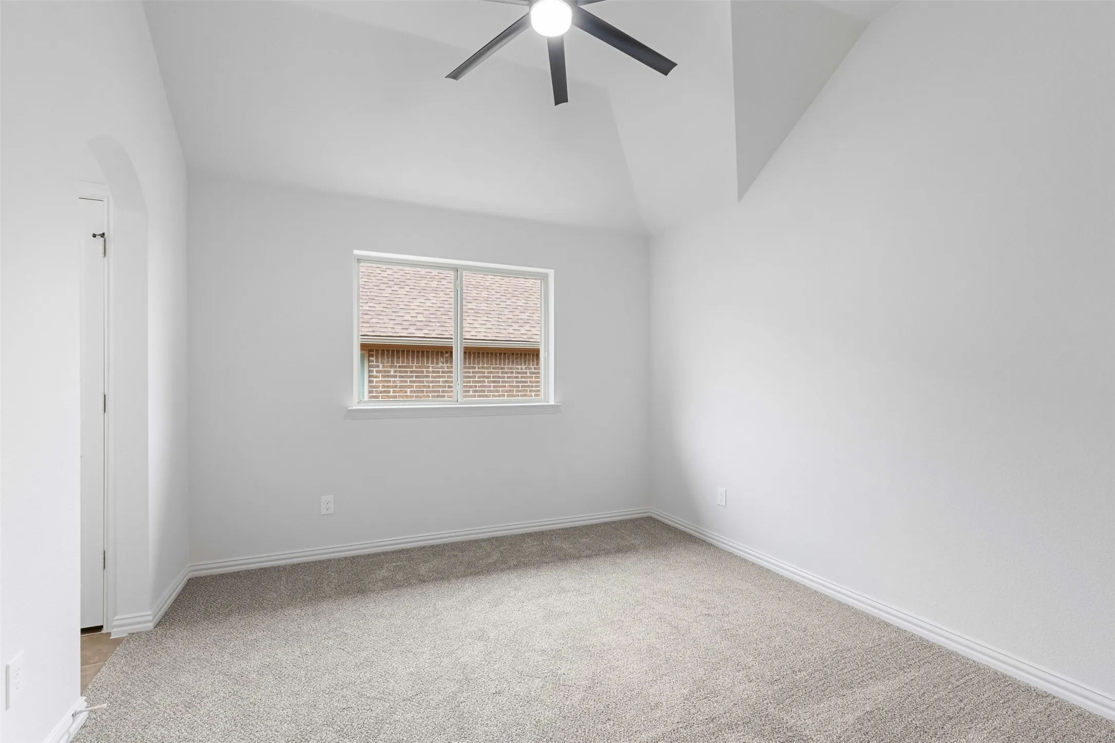 Spare room with arched walkways, light colored carpet, baseboards, a ceiling fan, and lofted ceiling