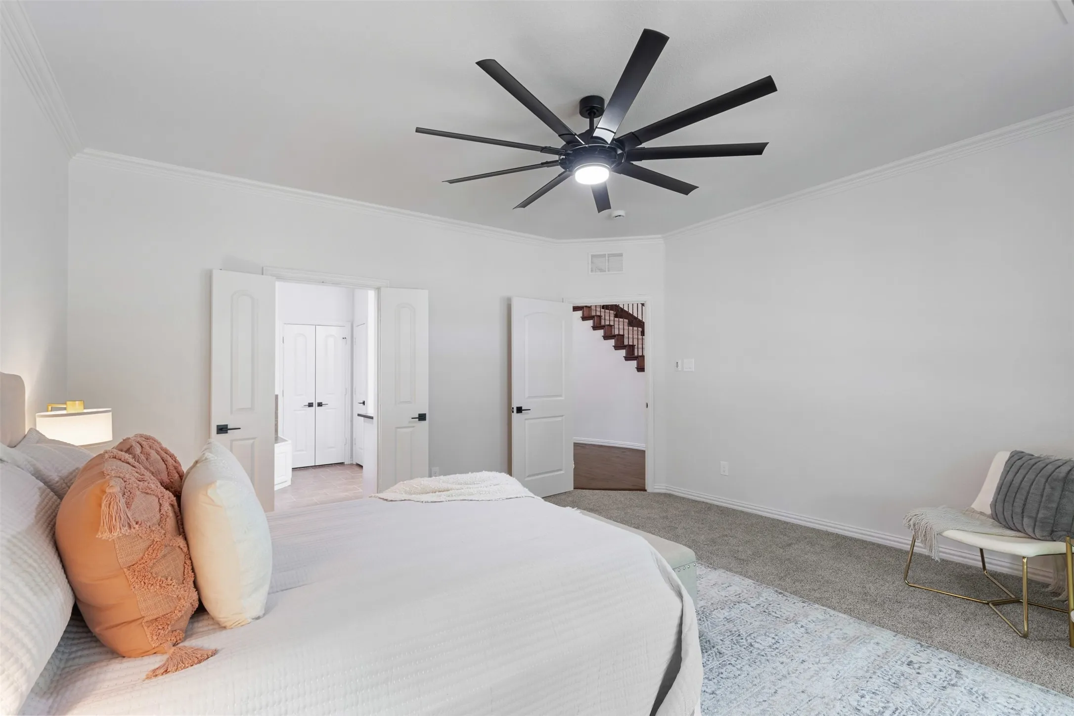 Carpeted bedroom featuring visible vents, ceiling fan, crown molding, and baseboards