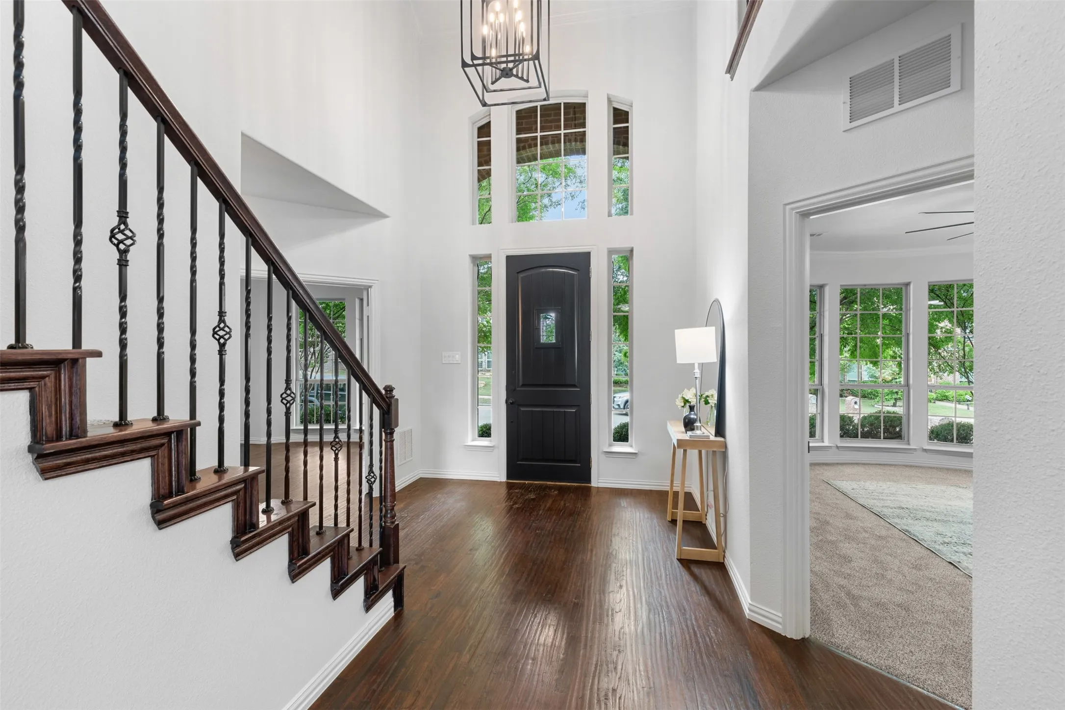 Entrance foyer featuring hardwood / wood-style flooring, a chandelier, visible vents, baseboards, and stairs