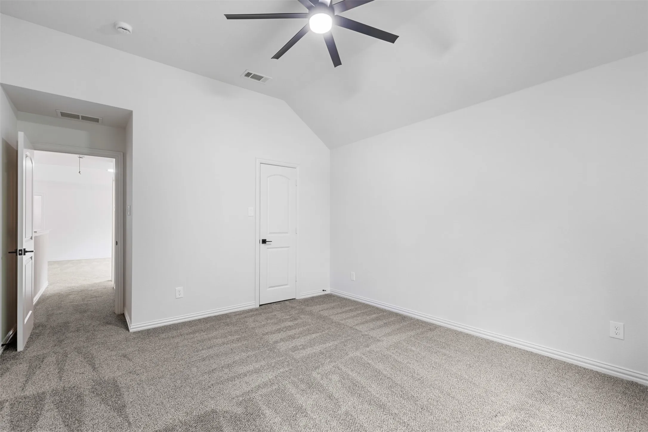 Unfurnished bedroom with lofted ceiling, visible vents, carpet floors, and baseboards