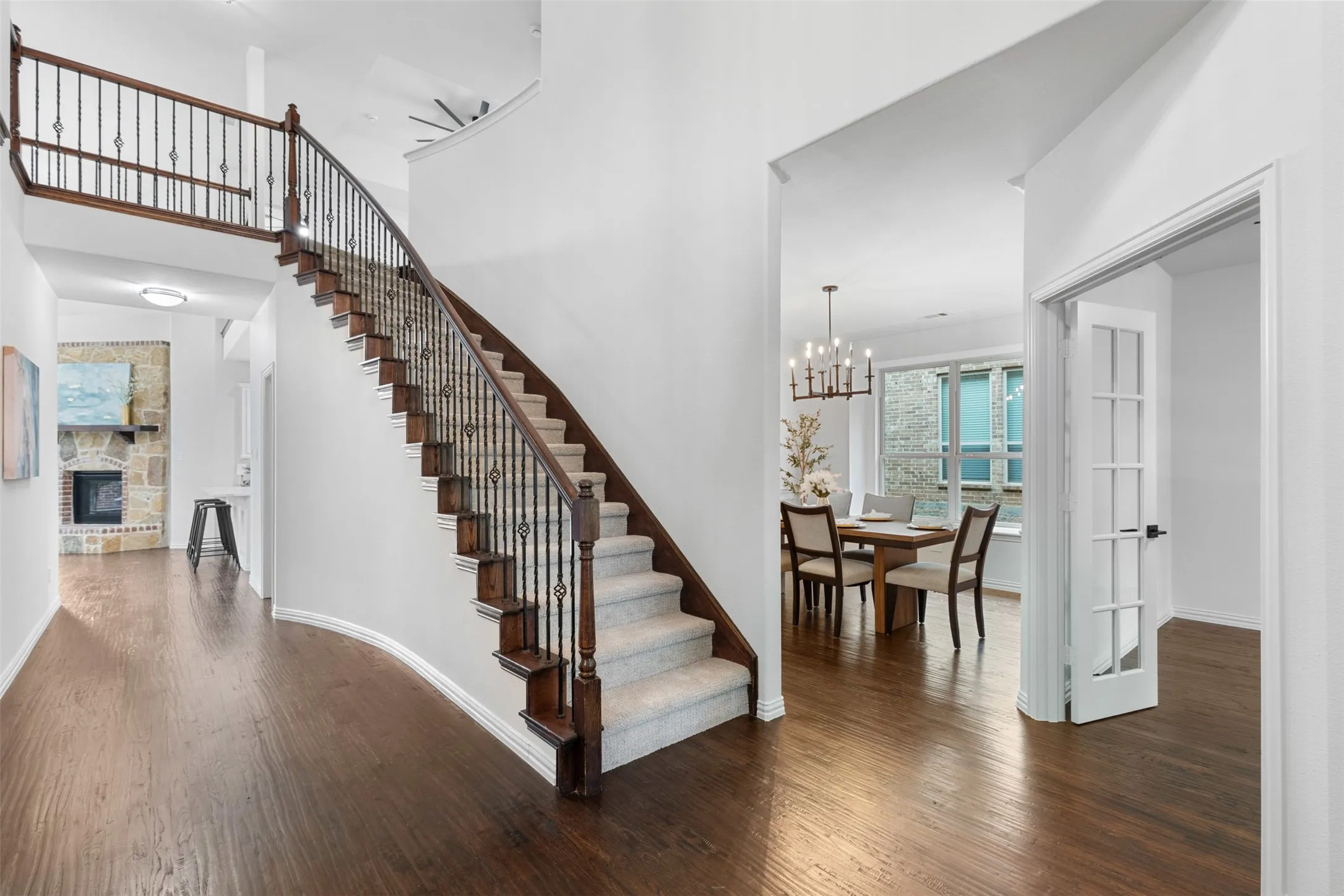 Staircase with wood finished floors, an inviting chandelier, a fireplace, baseboards, and a towering ceiling