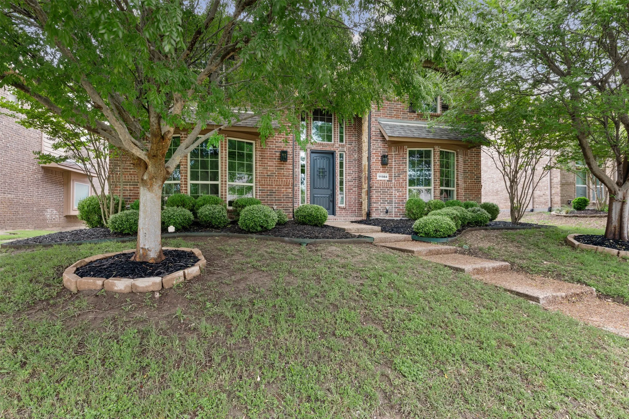 Obstructed view of property featuring a front lawn and brick siding