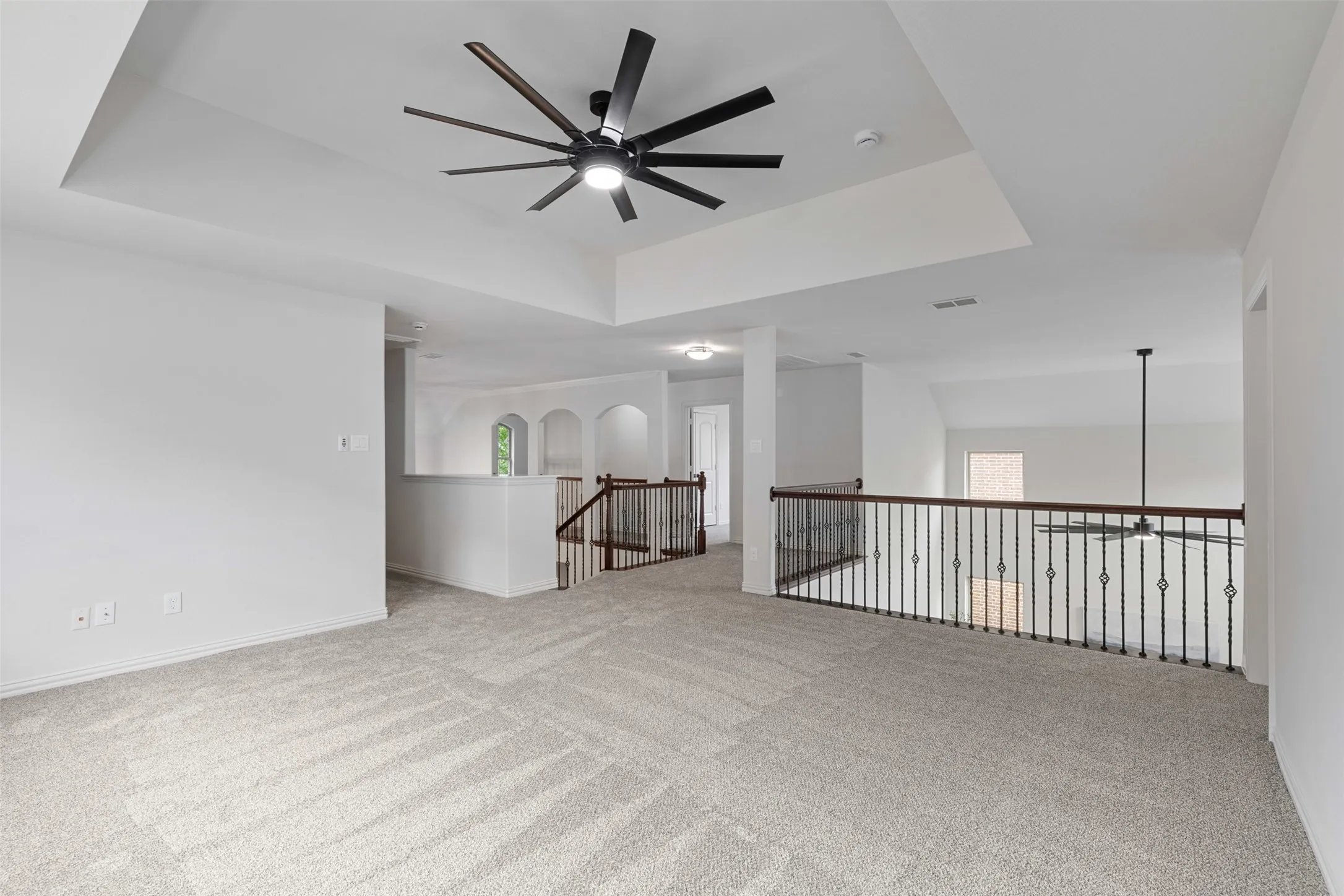 Empty room featuring baseboards, a raised ceiling, a ceiling fan, and carpet flooring