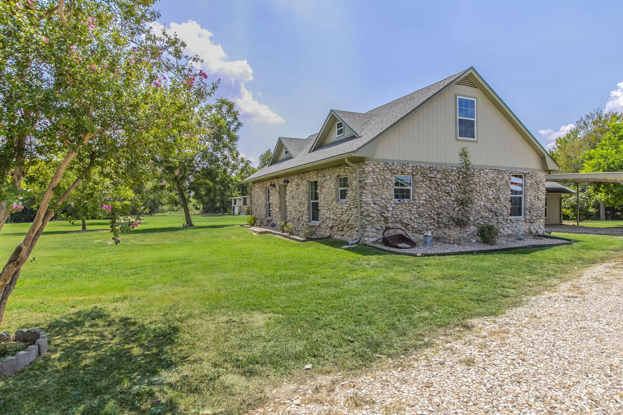 View of property exterior with stone siding and a lawn