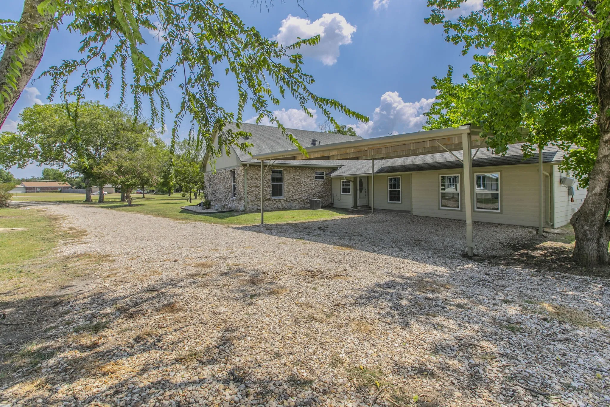 Rear view of house featuring a shingled roof, a patio area, brick siding, and a lawn
