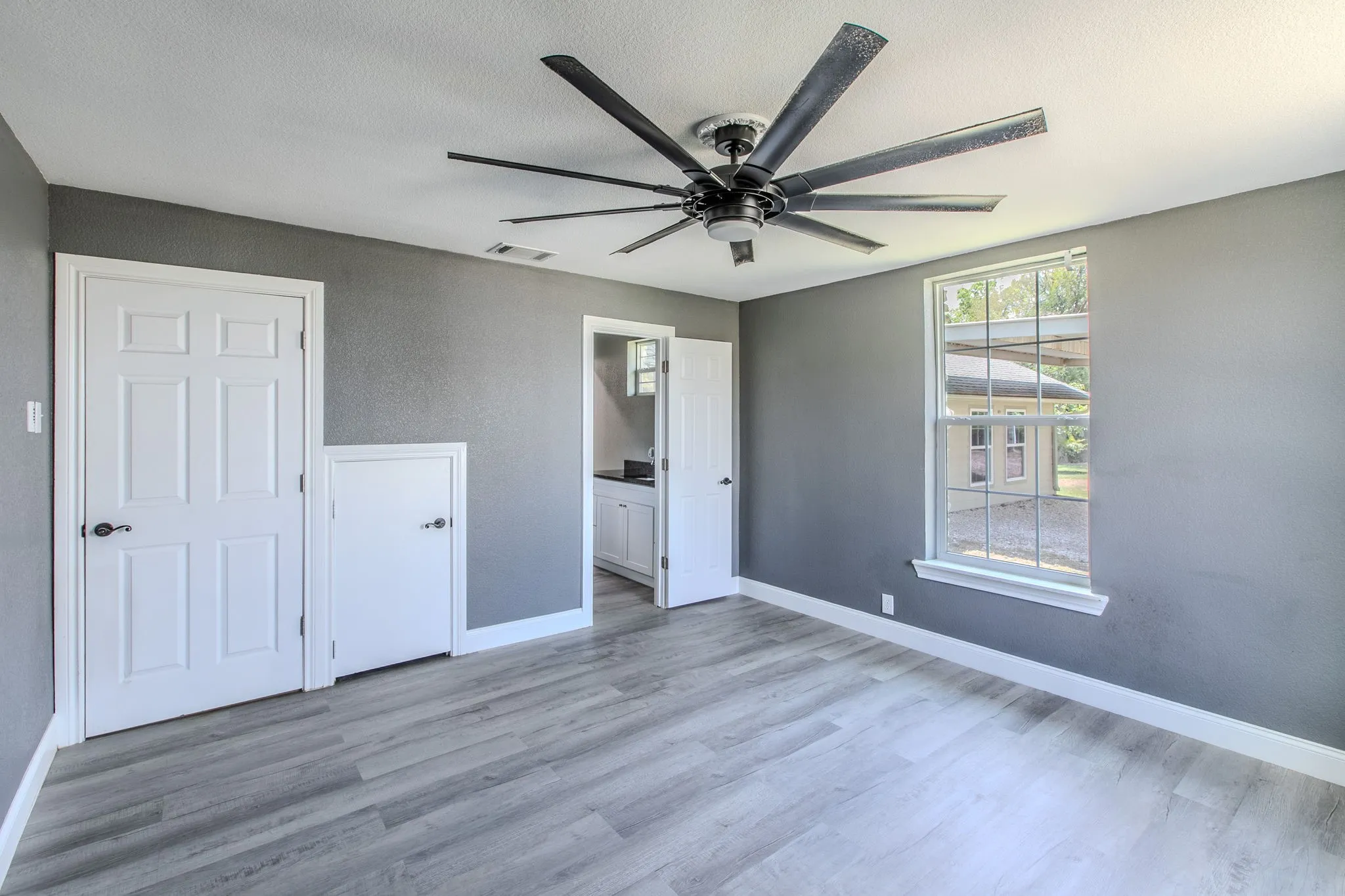 Unfurnished bedroom featuring connected bathroom, light wood finished floors, ceiling fan, and a textured ceiling