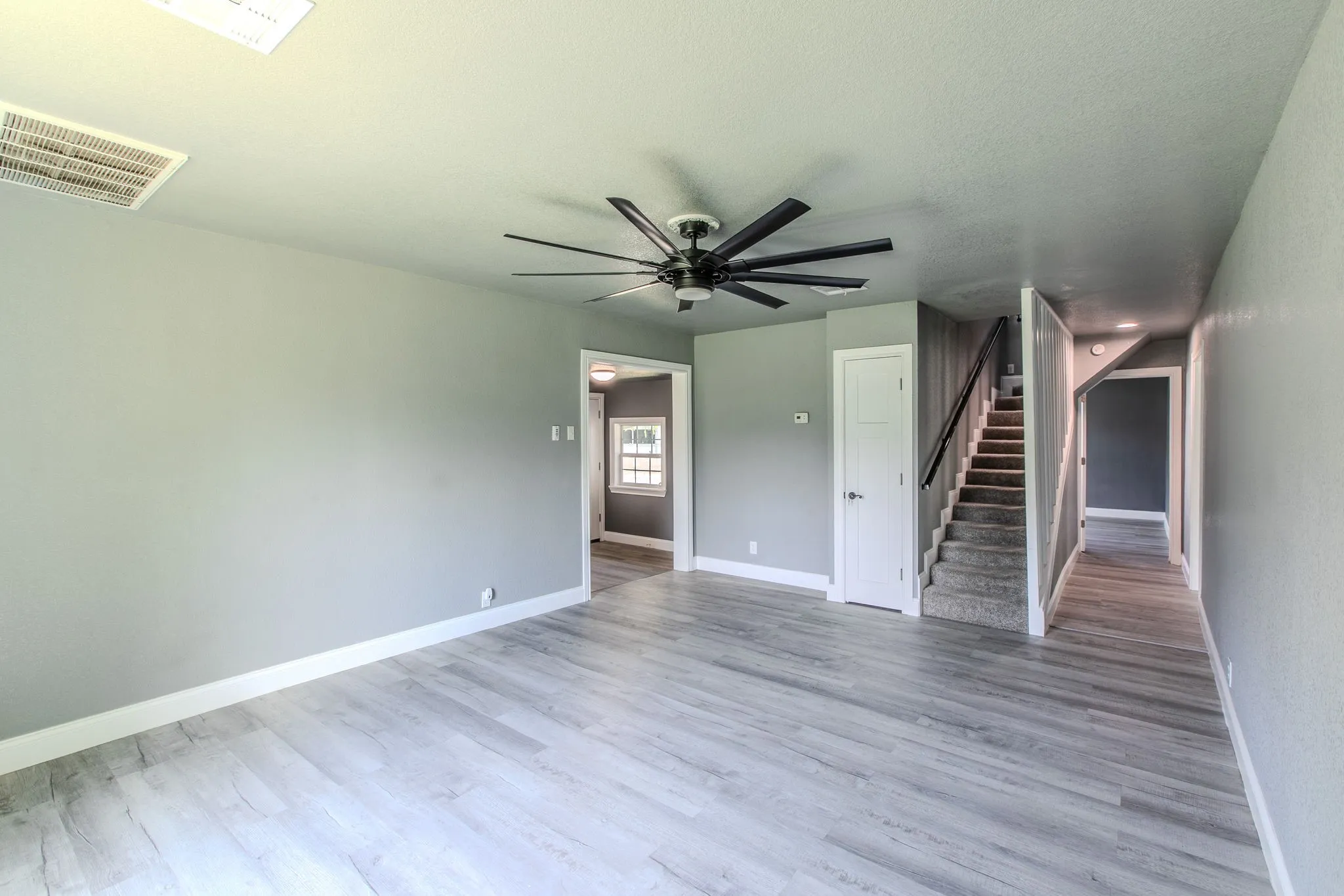 Unfurnished living room featuring light wood finished floors, stairs, and a ceiling fan